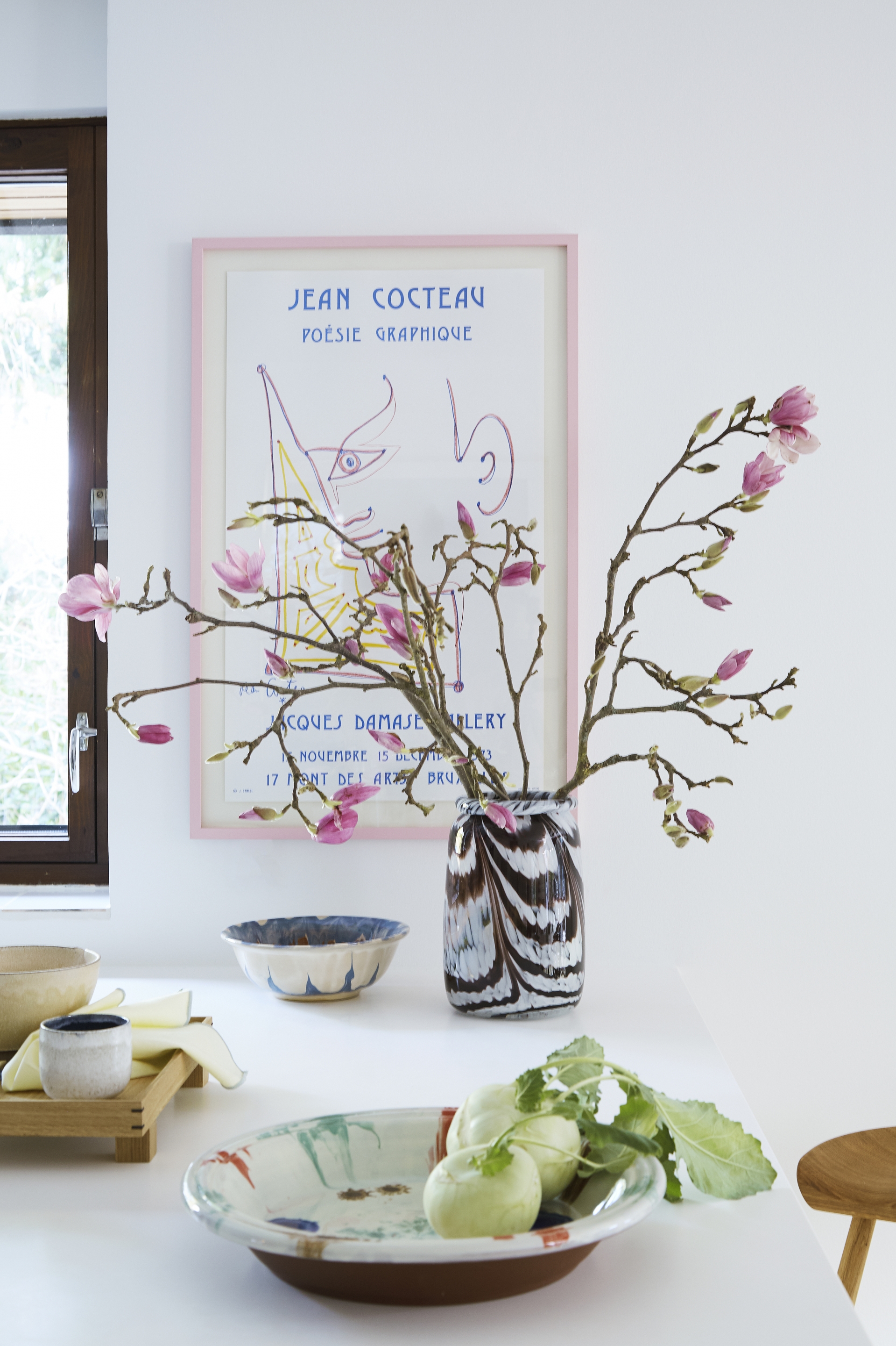 Một tấm áp phích độc đáo được đóng khung treo lên bức tường để trang trí. Lọ cắm hoa, chén đĩa bằng sứ bóng đẹp với kiểu dáng cổ điển và hoa văn lạ mắt.