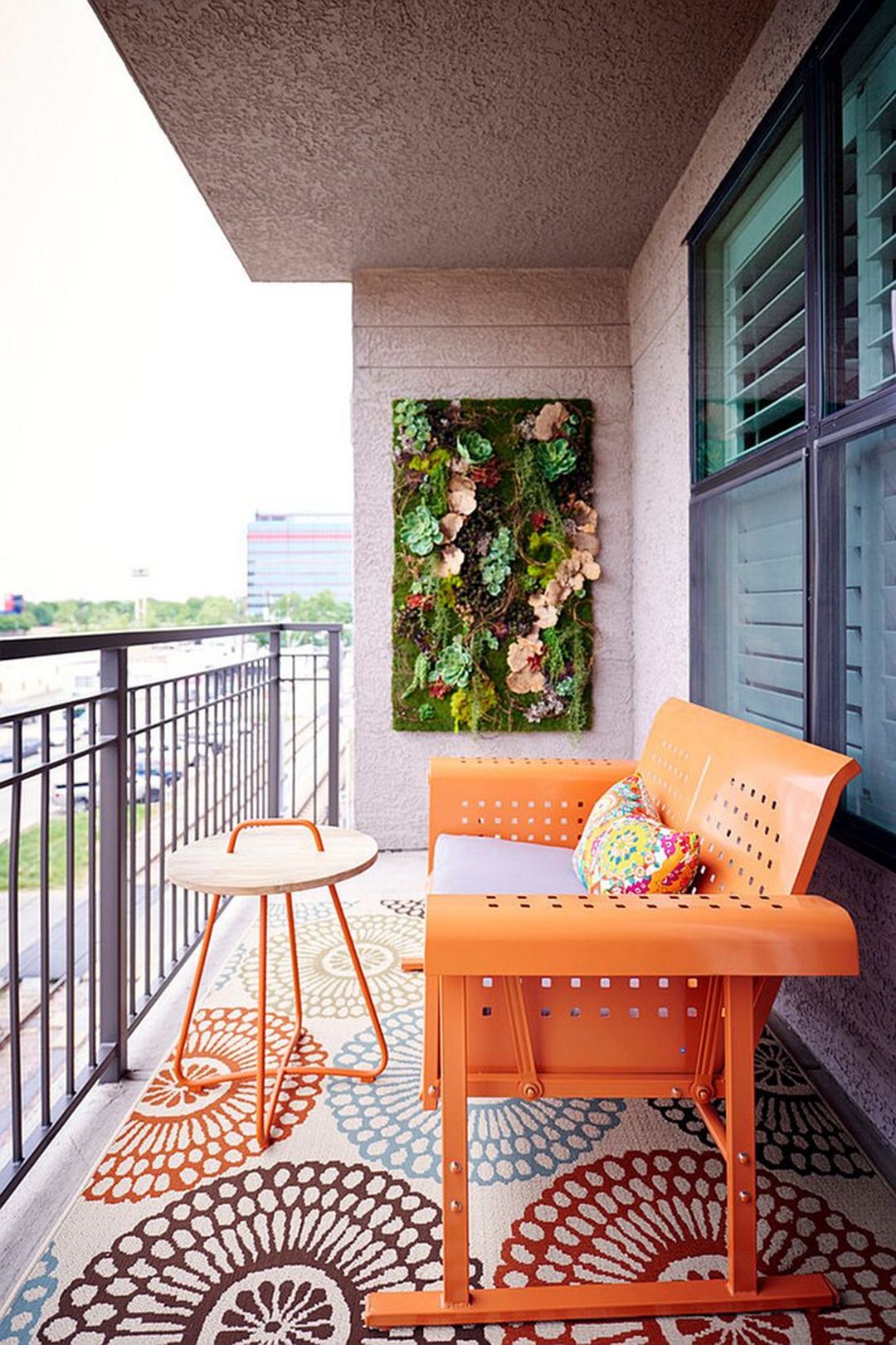 Ban công sở hữu những gì ấn tượng nhất: Một khu vườn thu nhỏ trên tường, một tấm thảm hoa văn to bản lôi cuốn và một chiếc ghế màu cam neon hút mắt vô cùng.