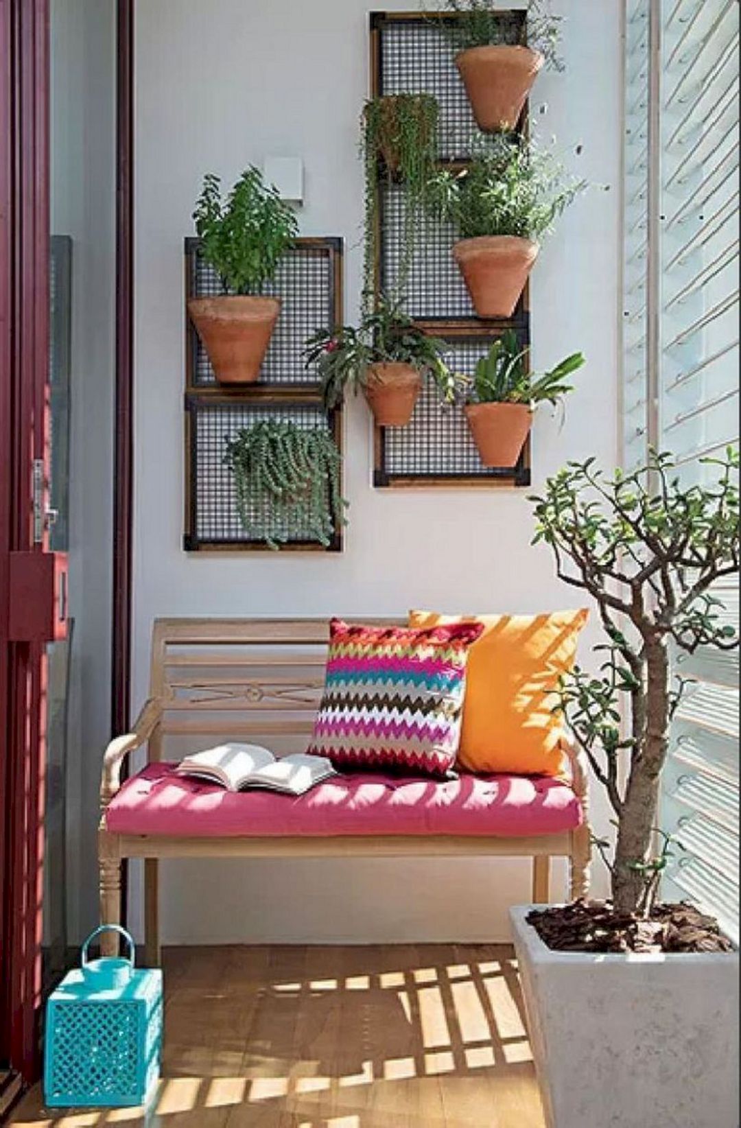 Bức tường sinh động với những chậu cây bằng gốm được trồng thẳng đứng, giúp giải phóng mặt sàn, nhường vị trí cho chiếc ghế gỗ với đệm màu hồng và gối tựa rực rỡ.
