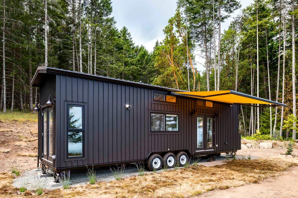 Ngôi nhà nhỏ xây dựng trên bánh xe với ngoại thất màu đen bí ẩn cùng sắc cam của mái hiên cuộn làm điểm nhấn.