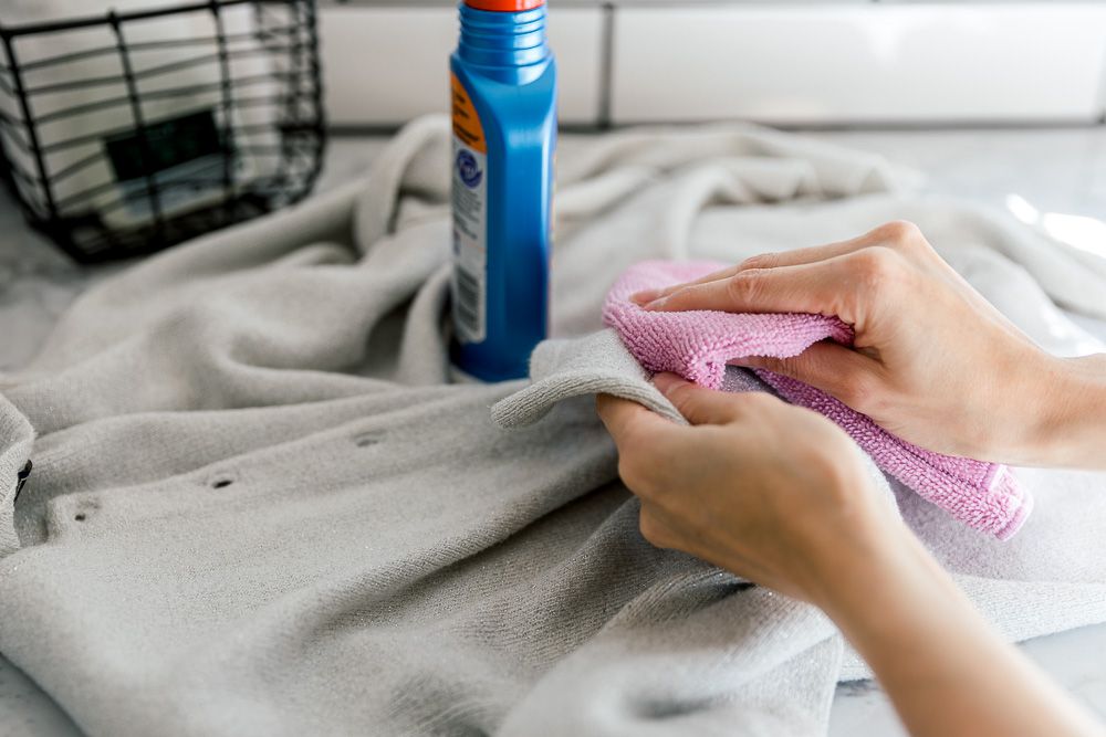 Dùng khăn nhỏ thấm một ít dung dịch giặt đồ len rồi chấm lên vết bẩn.