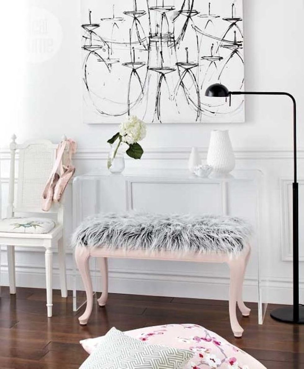 Một chiếc ghế dài với phần chân sơn màu hồng pastel và tấm lông màu xám trắng cho lối vào nhà đầy ấm áp và mời gọi.