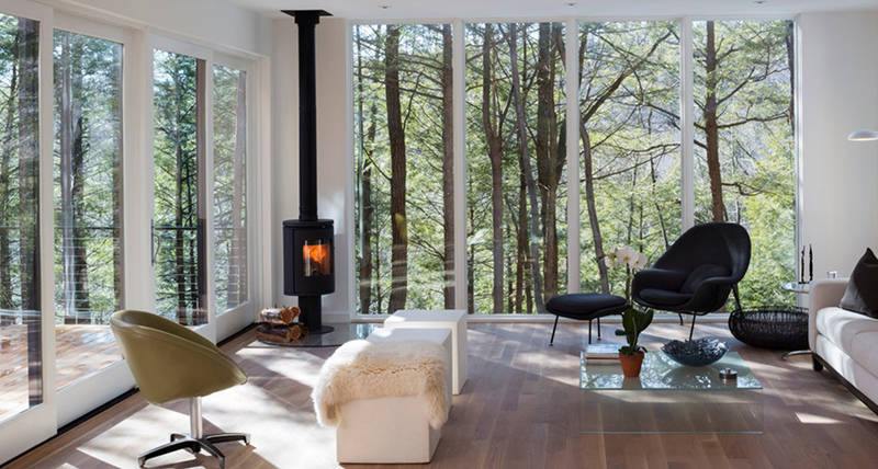 Phòng khách tuyệt đẹp với hai bức tường lắp đặt cửa kính trong suốt nhìn ra cánh rừng lãng mạn bên ngoài.