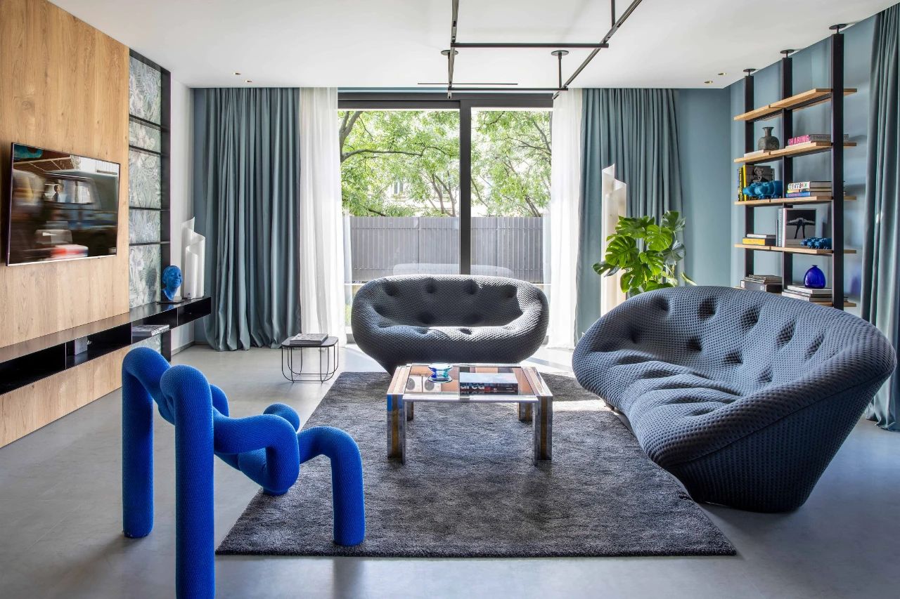 Lại gần khu vực phòng khách, bạn sẽ thấy chủ nhân đầu tư bộ ghế sofa có thiết kế cực đẹp với những đường cong mềm mại và gam màu xám của đá phiến và một chiếc ghế đơn siêu lạ với màu xanh neon không thể nổi bật hơn!