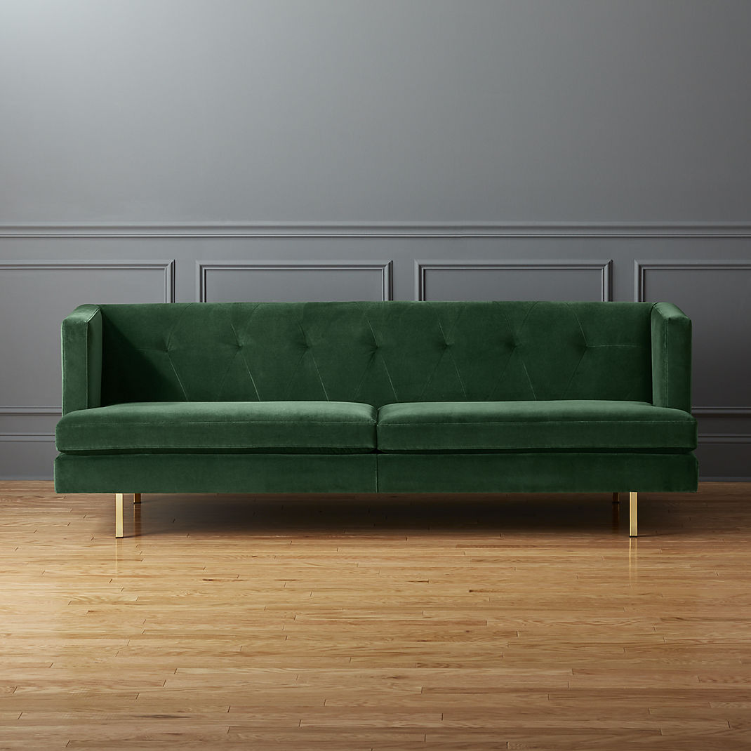 Chiếc ghế sofa nhung màu xanh lá cây tuyệt đẹp giữa căn phòng với bức tường màu xám thanh lịch và sàn gỗ nhẹ nhàng, ấm áp.