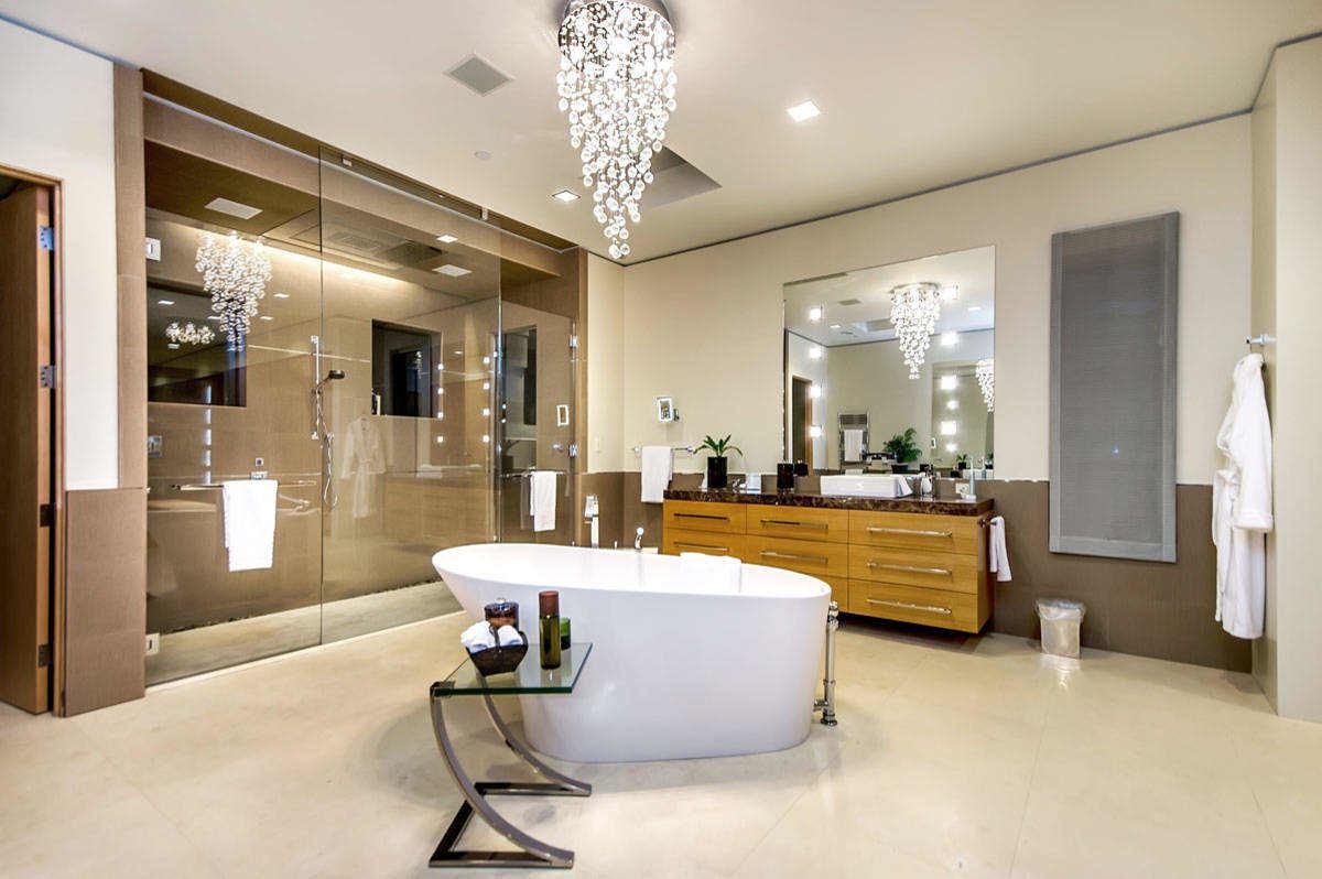 Chiếc đèn chùm xếp tầng lộng lẫy tạo điểm nhấn sang trọng cho phòng tắm rộng lớn.