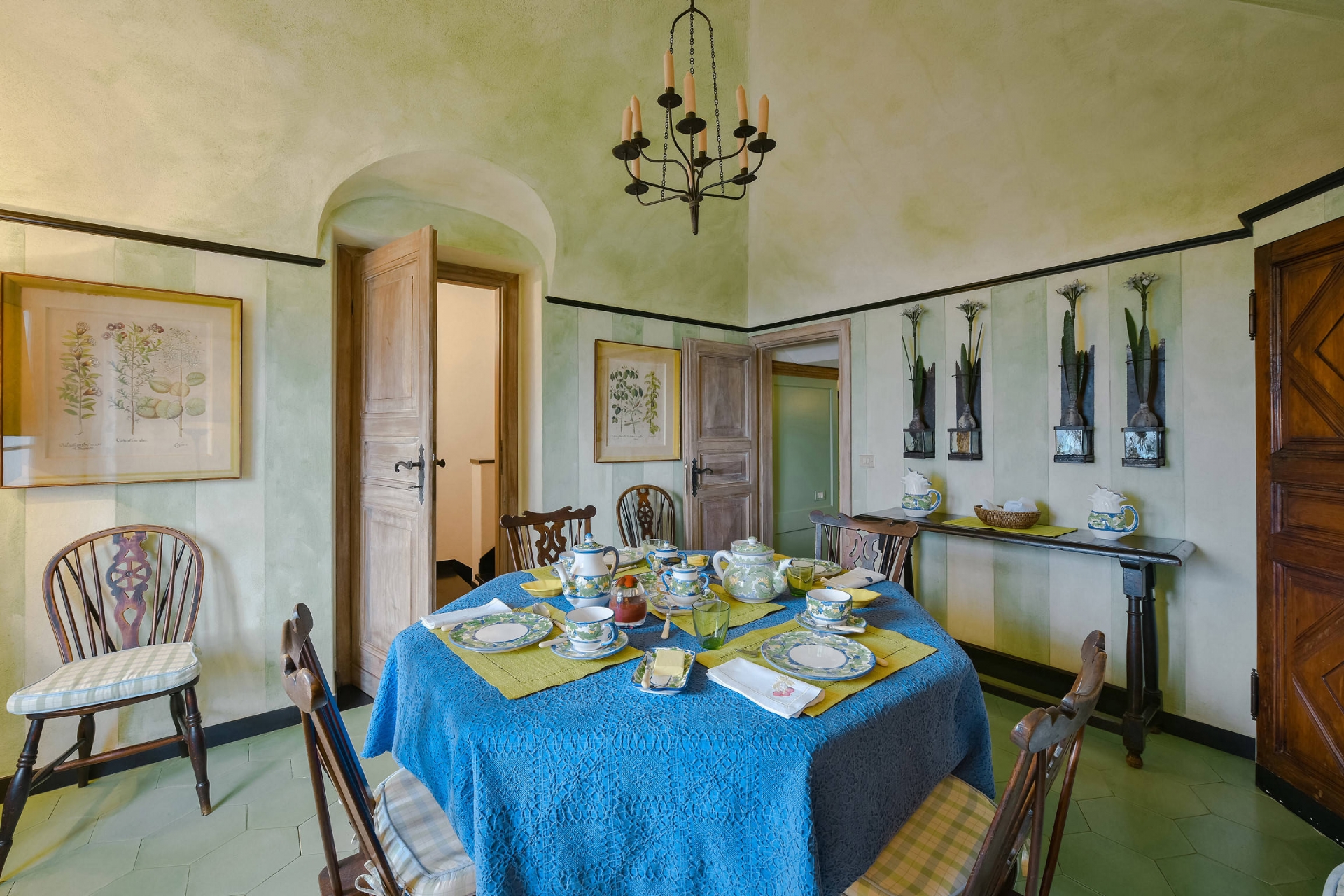 Phong cách Địa Trung Hải trong phòng ăn với bức tường màu xanh lá họa tiết kẻ sọc màu nhạt và sàn lát gạch họa tiết lục giác tươi mát.