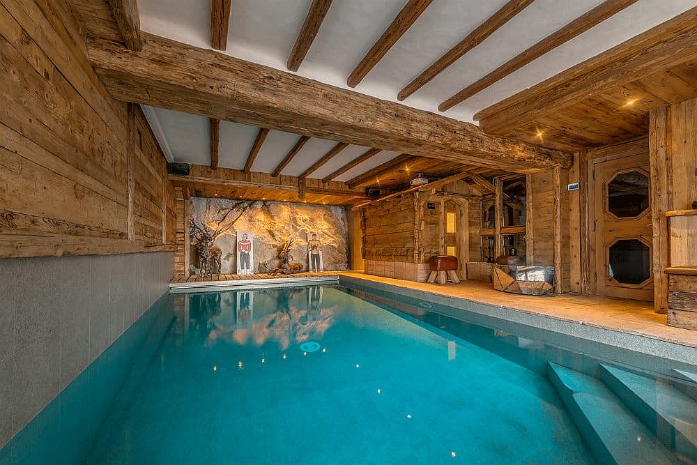 Bể bơi trong nhà siêu rộng với bức tường, cửa và dầm gỗ cho cảm giác ấm áp bao phủ xung quanh.