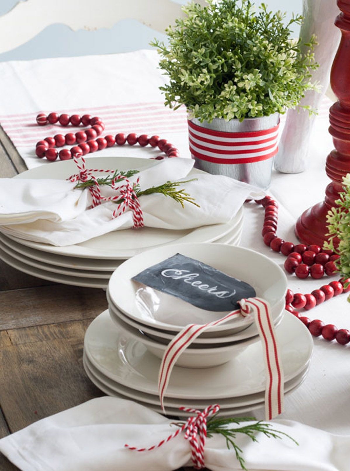 Tạo phông nền đơn giản với màu đỏ -trắng truyền thống mùa lễ hội: Dây ruy băng kẻ sọc, chuỗi hạt màu đỏ mô phỏng quả nam việt quất và sợi dây nhỏ buộc khăn ăn.