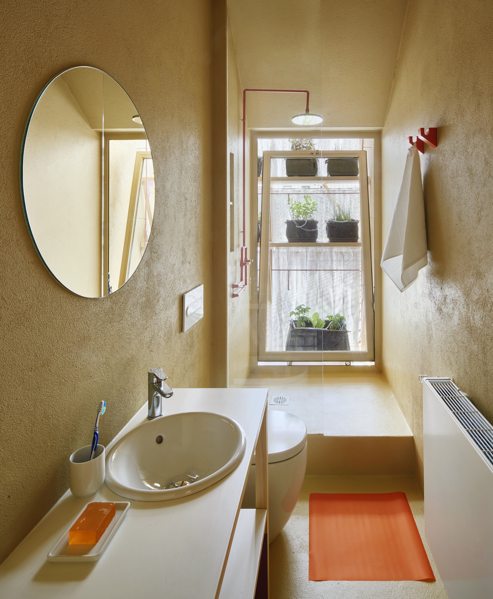 Phòng tắm có thiết kế đơn giản nhưng ấn tượng với ô cửa kính cùng những điểm nhấn màu cam bắt mắt.