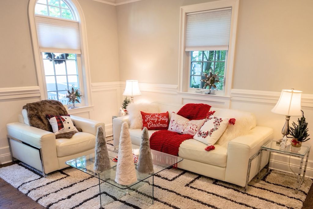 Phòng khách nhẹ nhàng với hai gam màu trắng đỏ cùng nhiều phụ kiện ấm áo như chăn bông, gối tựa, thảm trải sàn cho đến những cây thông mini cách điệu trang trí trên bàn nước.