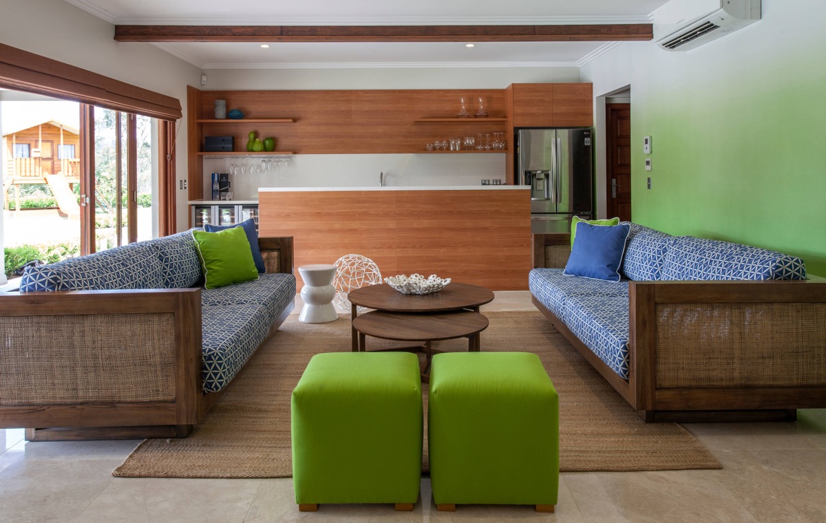 Bức tường lựa chọn cả hai gam màu trắng và xanh lá cây, ghế sofa xanh lam kết hợp gối tựa và ghế đôn màu xanh ô liu cùng nội thất gỗ cho cái nhìn vô cùng gần gũi.