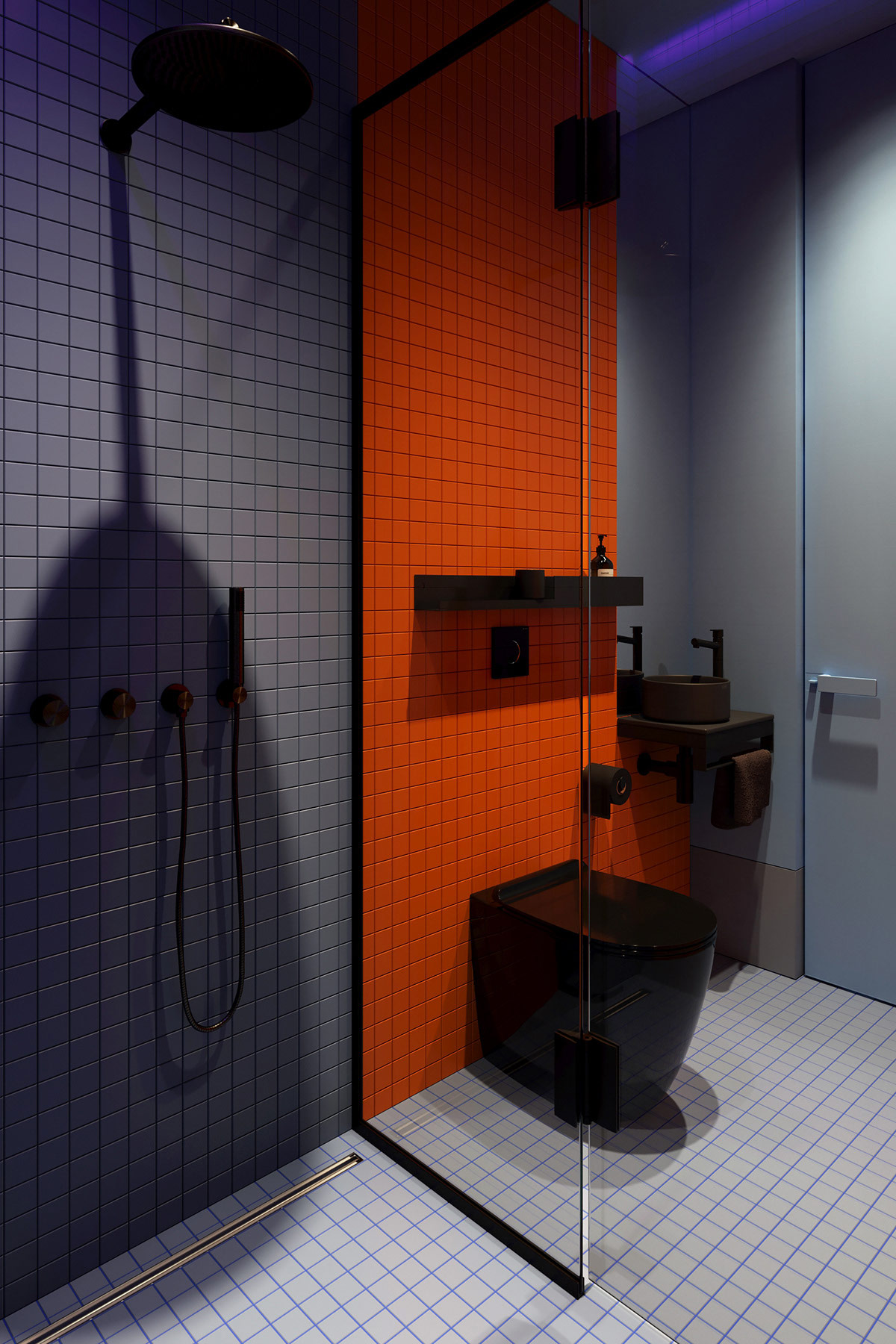 Phòng tắm nổi bần bật với bức tường màu xám, cam và sàn nhà màu trắng với keo chà ron màu xanh lam đẹp mắt. Cửa kính trong suốt phân vùng buồng tắm đứng và toilet một nhẹ nhàng và thông thoáng.