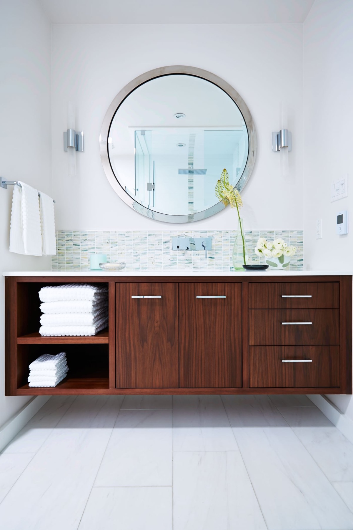 Một chiếc tủ vanity phát huy tối đa công dụng lưu trữ cho phòng tắm. Nó được làm bằng gỗ tối màu, bao gồm cả kệ mở, tủ có cửa đóng kín và cả các ngăn kéo linh hoạt cho nhiều vật dụng khác nhau.