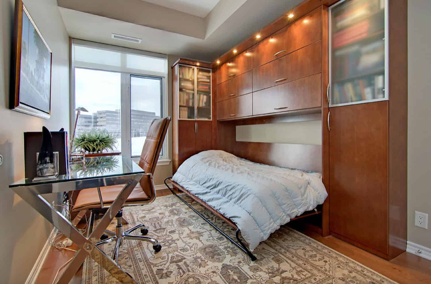 Chiếc giường Murphy bằng gỗ sậm màu tích hợp trong tủ sách cực lớn, đối diện góc làm việc tại gia. Kích thước giường đơn cho phép bạn ngả lưng nghỉ ngơi hoặc dành cho khách đến thăm nhà ngủ lại.