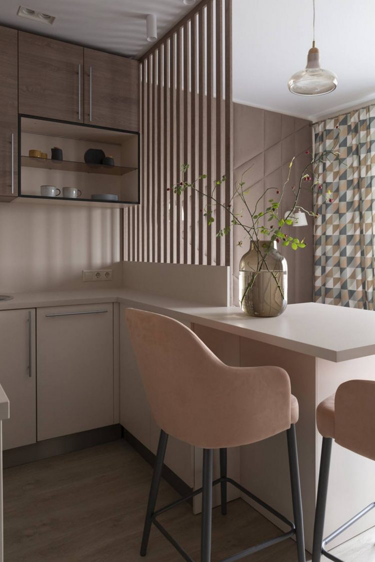 Hệ tủ bếp trên màu gỗ tự nhiên tạo nên sự tương phản với hệ tủ bếp dưới màu trắng sáng sủa. Những chiếc ghế ăn màu hồng đào trông cực kỳ ngọt ngào và xinh xắn.