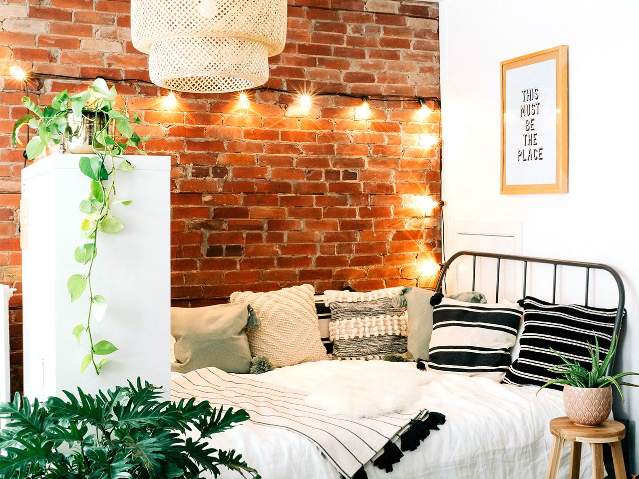 Chuỗi đèn chiếu sáng trên tường gạch cho cái nhìn lung linh, rực rỡ, kết hợp với cây xanh trang trí cân bằng sắc thái cho phòng ngủ này quyến rũ hơn rất nhiều.