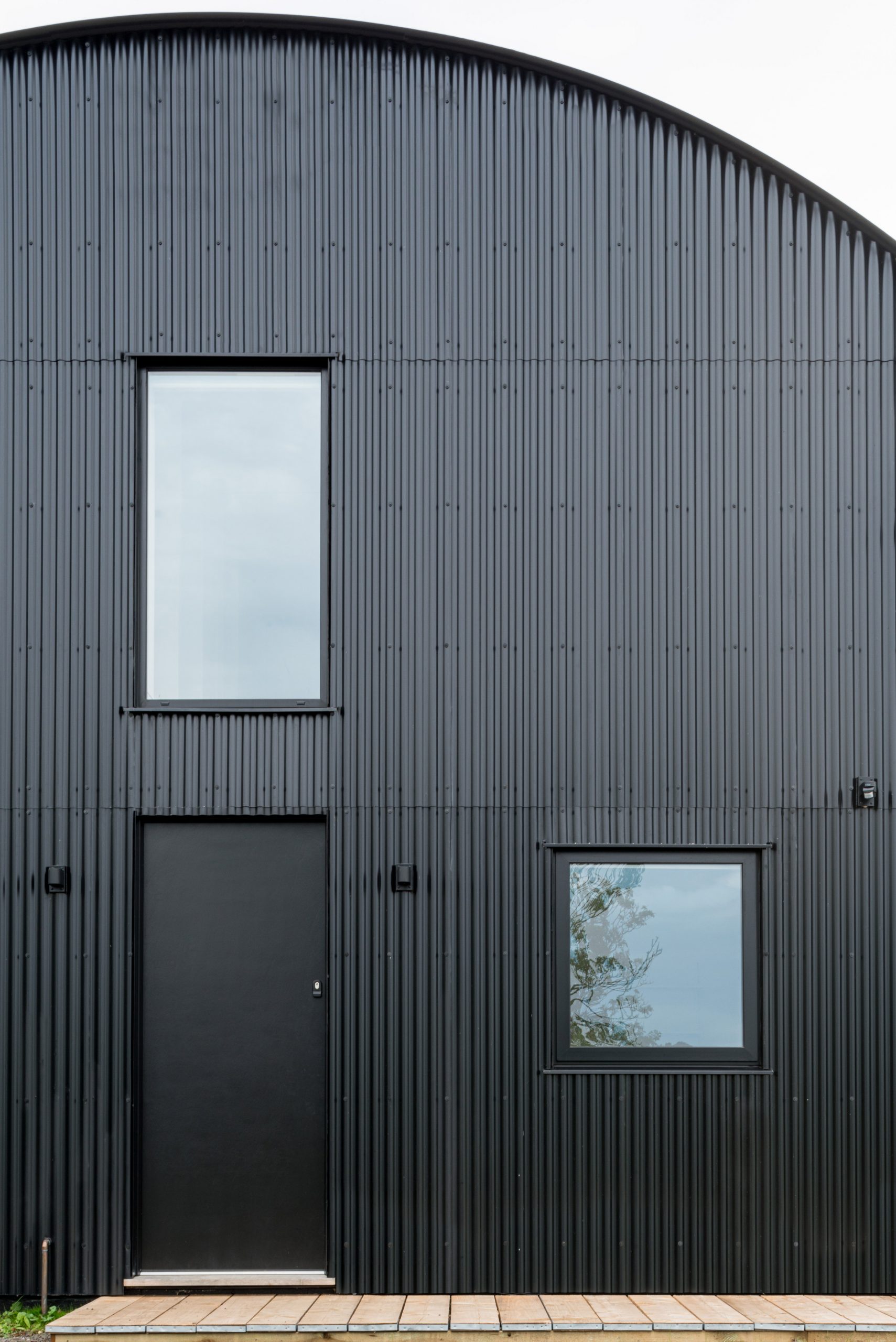 Thép tôn được bao phủ cả bức tường và mái nhà, tạo nên một lớp hoàn thiện màu đen mờ cho phần ngoại thất của DUT18. 