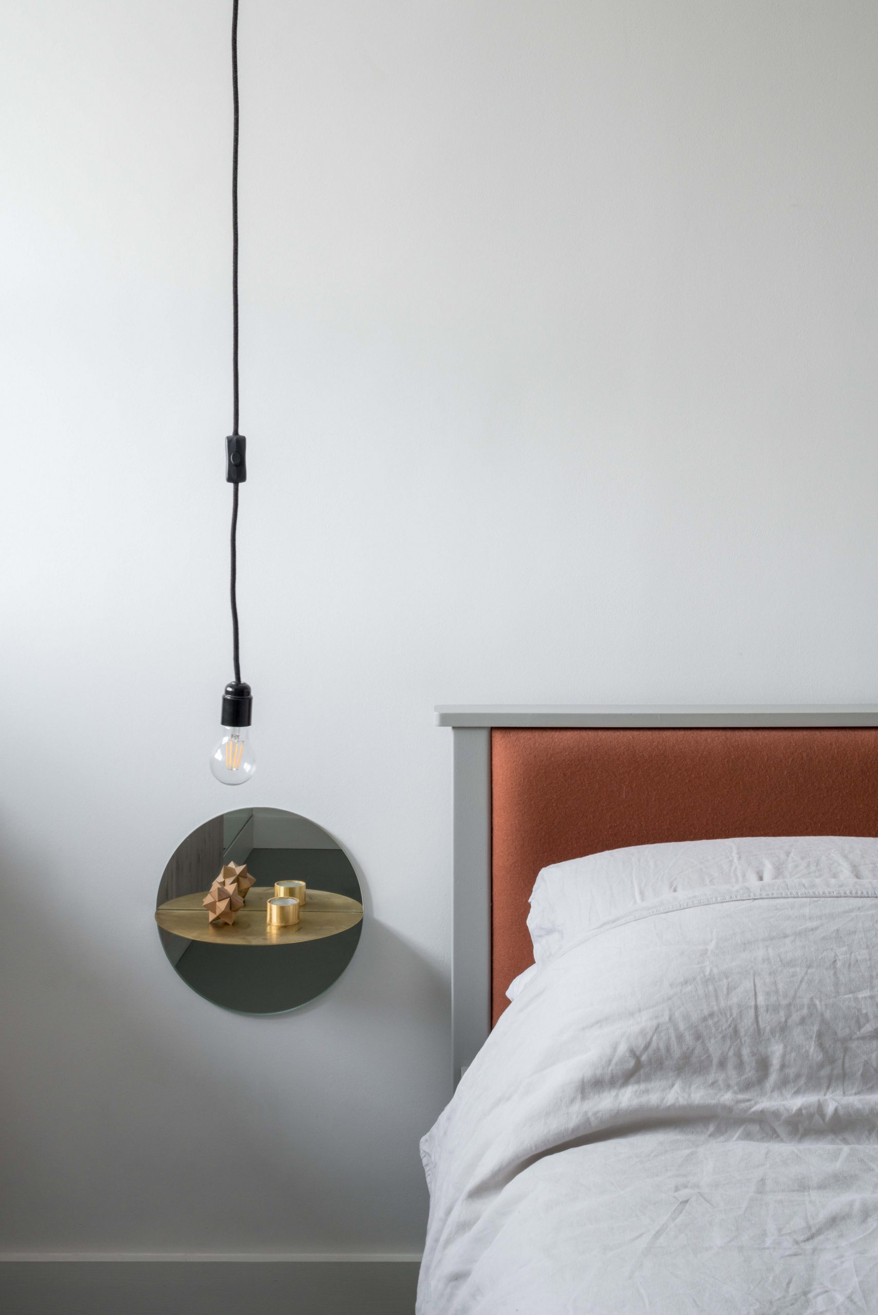 Thay vì sử dụng táp đầu giường nặng nề, thô cứng, chủ nhân căn hộ đã chọn sản phẩm của nghệ sĩ Olafur Eliasson với hình thức gắn tường cùng gương soi phản chiếu cho cái nhìn hiện đại và tinh giản.