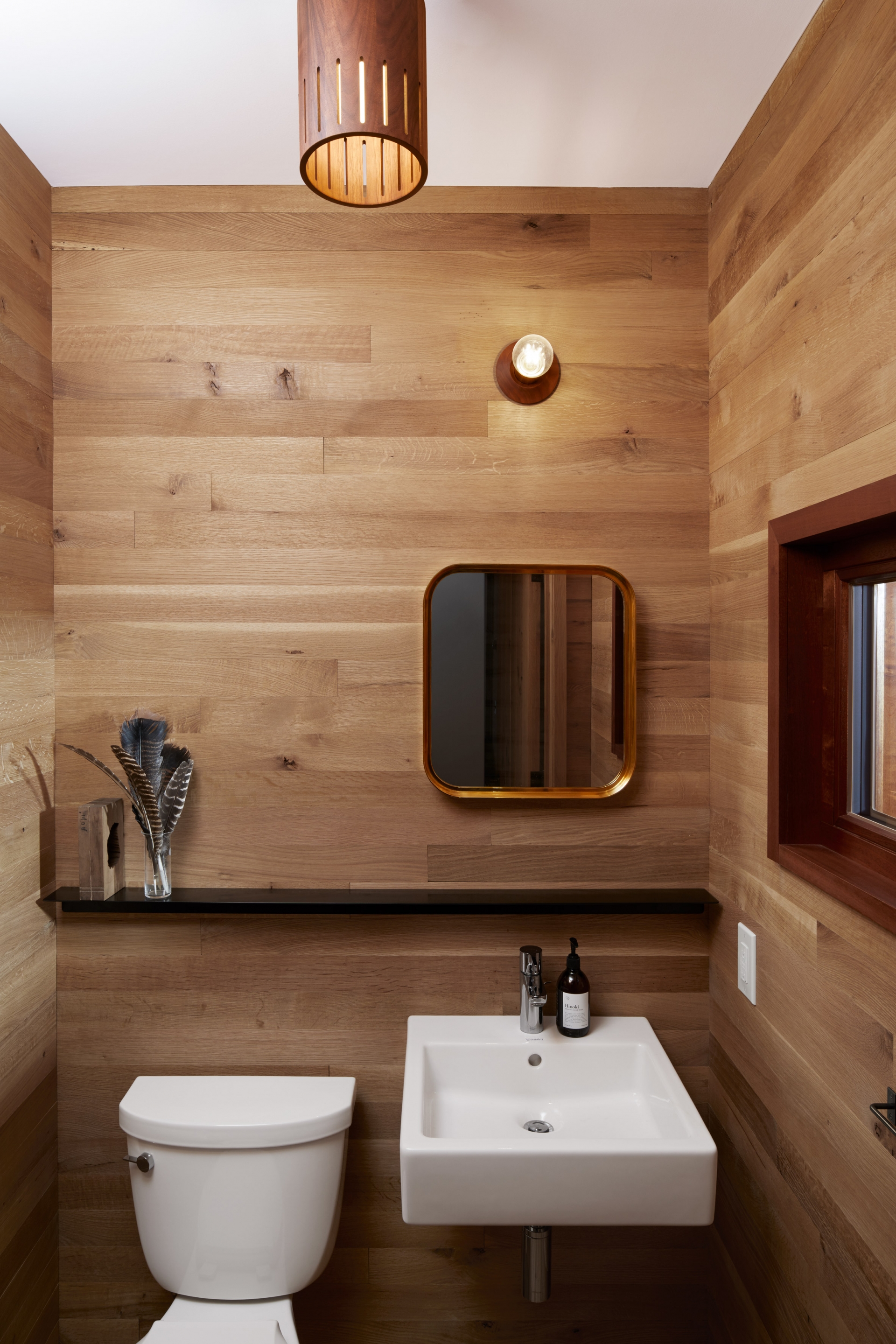 Phòng tắm kết hợp nhà vệ sinh tuy nhỏ nhưng tràn đầy cảm hứng với hệ thống đèn chiếu sáng ấm áp cùng nội thất gỗ màu trầm xua tan đi sự ẩm ướt và lạnh lẽo thường thấy trong phòng tắm.