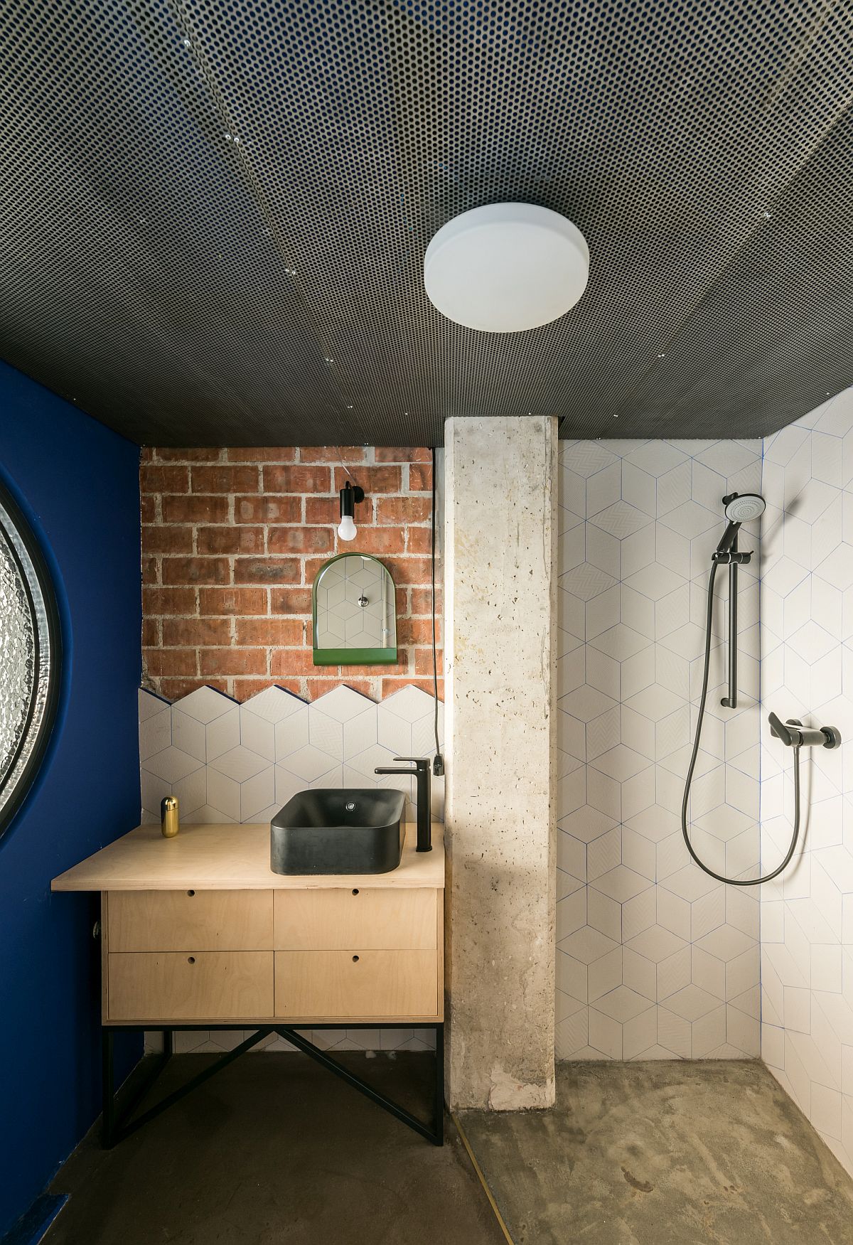 Các yếu tố kim loại, gạch, xi măng, ván ép nhiều họa tiết và kết cấu tương phản, kết hợp cùng bức tường sơn màu xanh lam đậm tạo nên một phòng tắm nhỏ nhưng “có một không hai”.