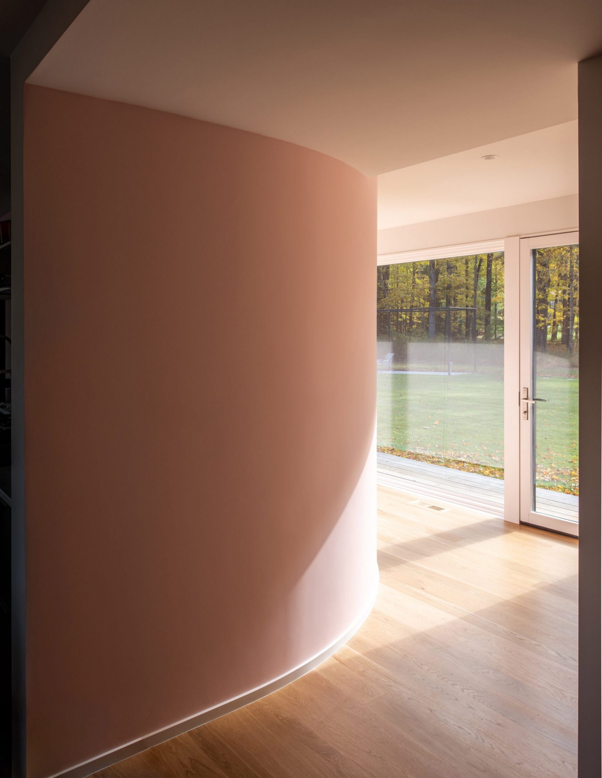 Cũng ở tầng trệt của ngôi nhà, các kiến trúc sư của Vondalwig Architecture đã tạo ra một bức tường với đường cong mềm mại dẫn lối, thay thế cho những bức tường vuông vức thường thấy. Bức tường được sơn màu hồng pastel ngọt ngào, tạo sự liên kết với nội thất của phòng khách thứ hai được mở rộng ở trên.