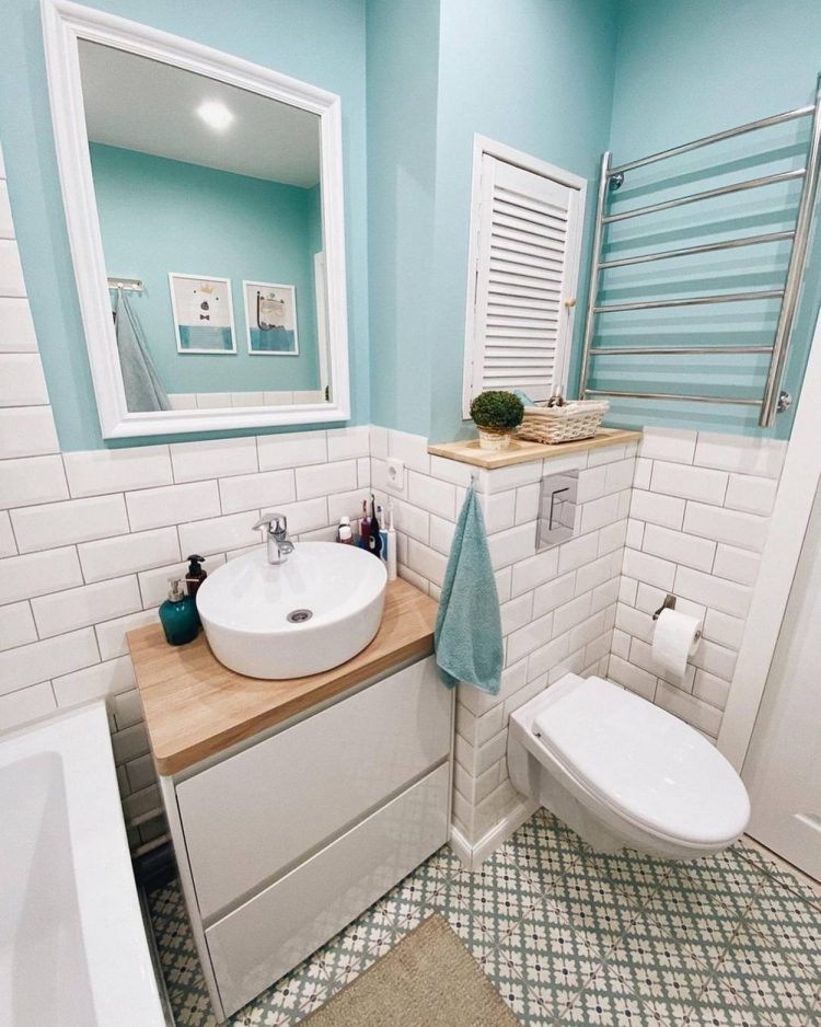 Phòng tắm chung nhỏ xinh với gạch bông lát sàn cùng bức tường được chia thành 2 phần, phần trên sơn màu xanh lam nhạt, phần dưới ốp gạch sáng bóng để dễ dàng vệ sinh. Tấm gương lớn vuông vức cũng góp phần “nhân đôi” diện tích căn phòng.