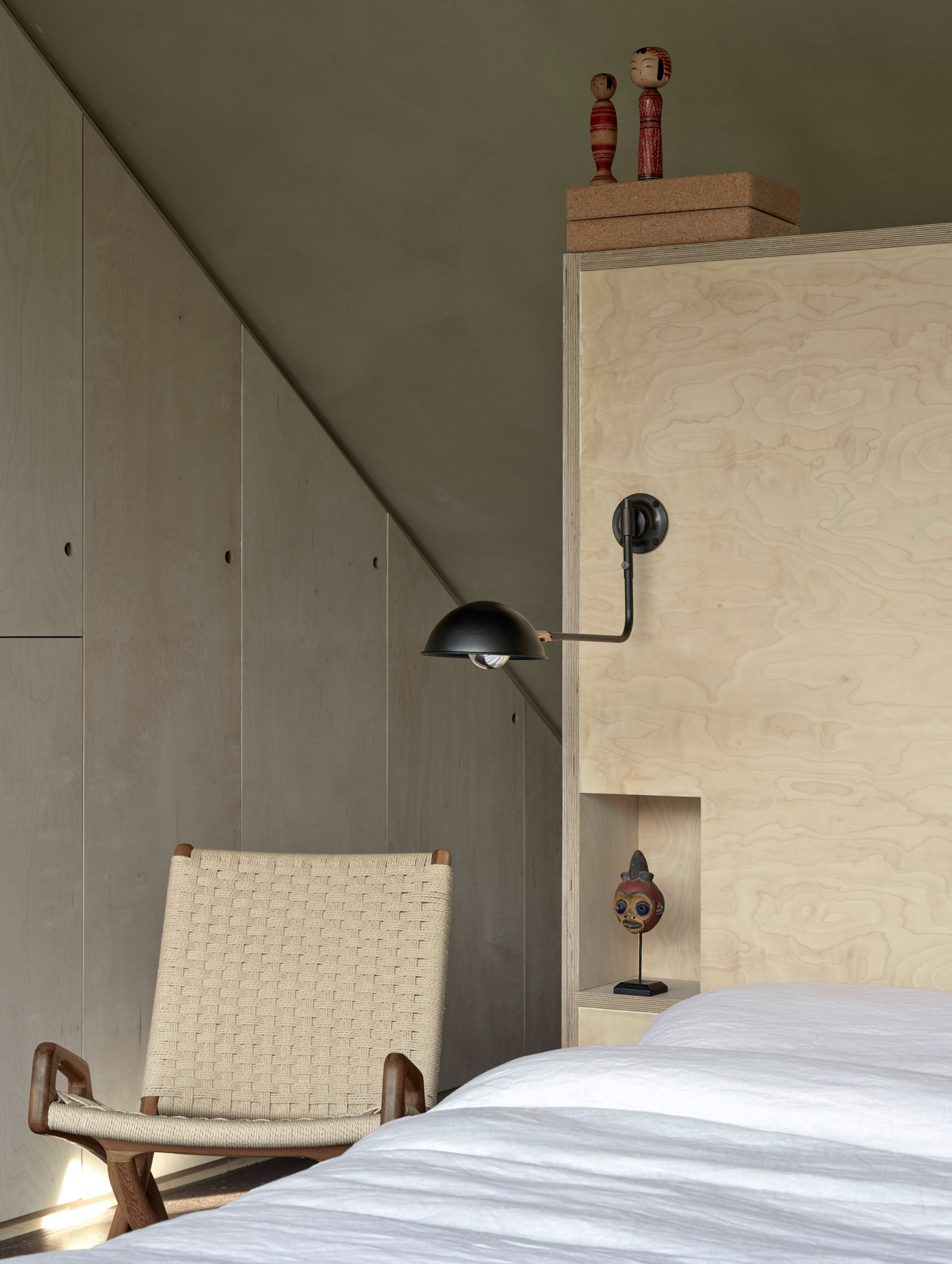 Hệ thống tủ lưu trữ bằng gỗ không tay nắm tạo nên sự đơn giản, gọn gàng cho căn phòng. Đầu giường tích hợp những hộc nhỏ để đựng những món đồ trang trí.