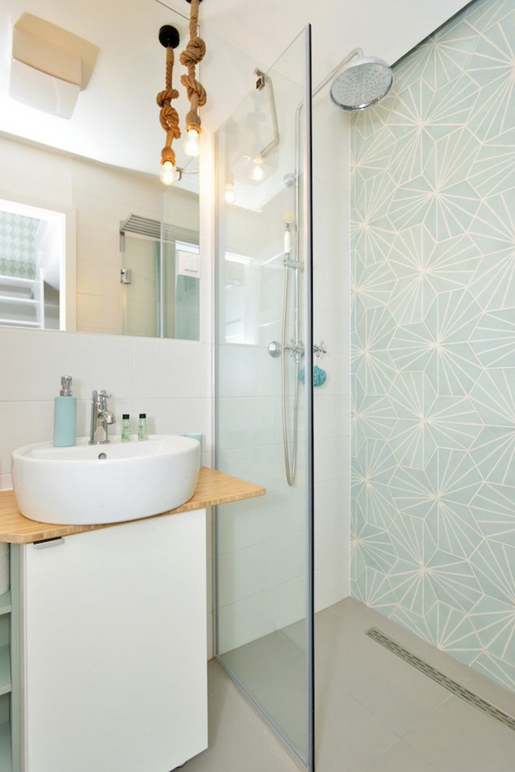 Phòng tắm siêu nhỏ với buồng tắm đứng phân cách với nhà vệ sinh và bồn rửa tay bằng cửa kính trong suốt. Bức tường họa tiết hình học đẹp mắt với màu xanh bạc hà cũng khiến phòng tắm trông đáng yêu hơn.