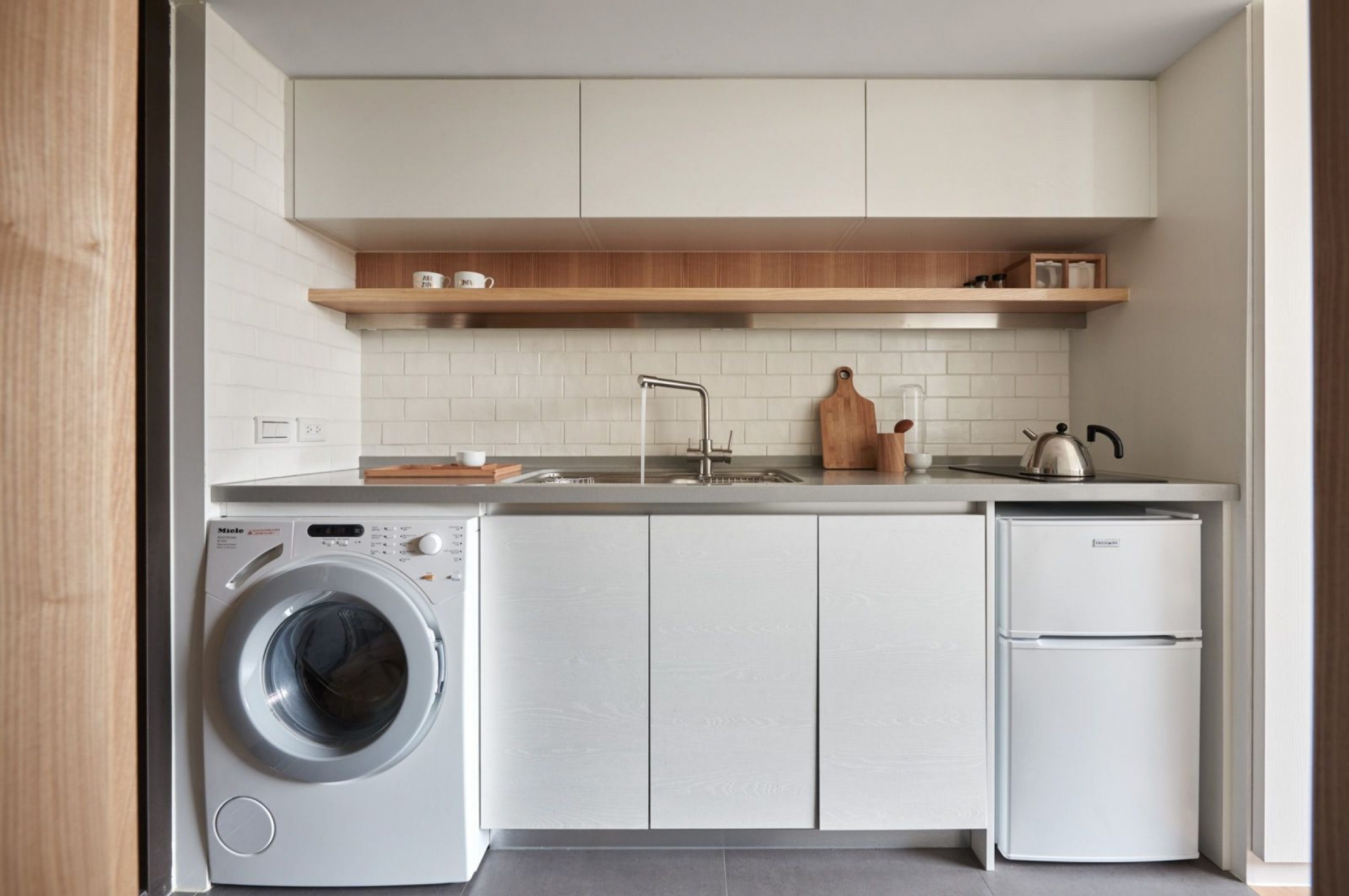 Khi cải tạo căn hộ, A Little Design đã quyết định di dời vị trí của chiếc máy giặt từ phòng tắm sang khu vực phòng bếp, ngay dưới mặt bàn bếp để tiết kiệm không gian.