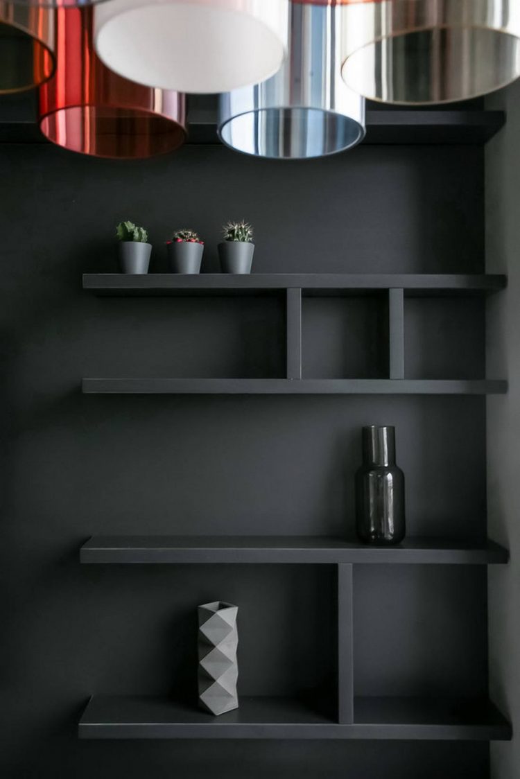 Kệ mở lưu trữ được nhà thiết kế phân bổ ở nhiều nơi trong căn hộ, đặc biệt là trên các bức tường màu xám đen khiến chúng hòa lẫn vào bức tường, giống như những chú tắc kè hoa đổi màu để khó ai có thể nhận ra sự hiện diện của mình. 