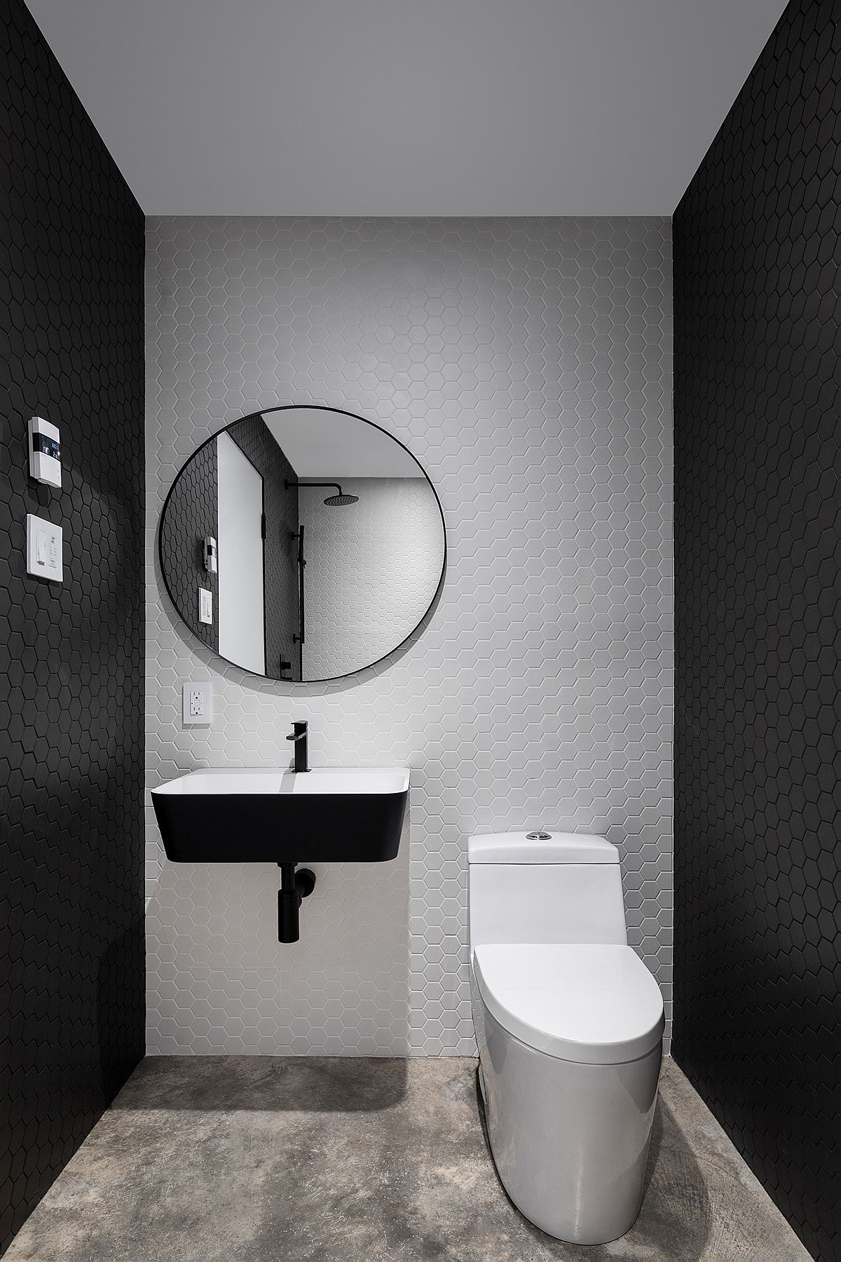 Phòng tắm sử dụng gạch họa tiết tổ ong đẹp mắt với hai gam màu trắng - đen cổ điển tạo chiều sâu cho không gian. Tấm gương tròn cùng bồn rửa gắn tường làm nên điểm nhấn cho bức tường màu trắng.