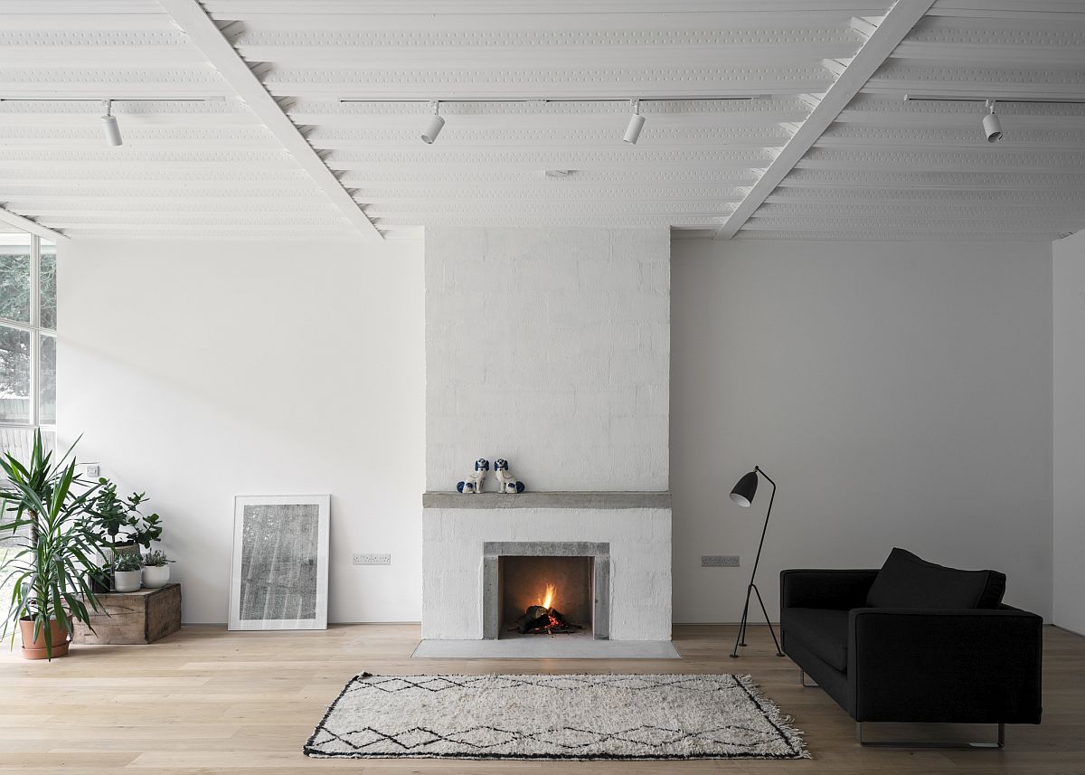 Phòng khách thiết kế tối giản với ghế sofa và đèn sàn màu đen làm điểm nhấn nổi bật, thảm trải sàn và lò sưởi cho cảm giác ấm áp thân mật.