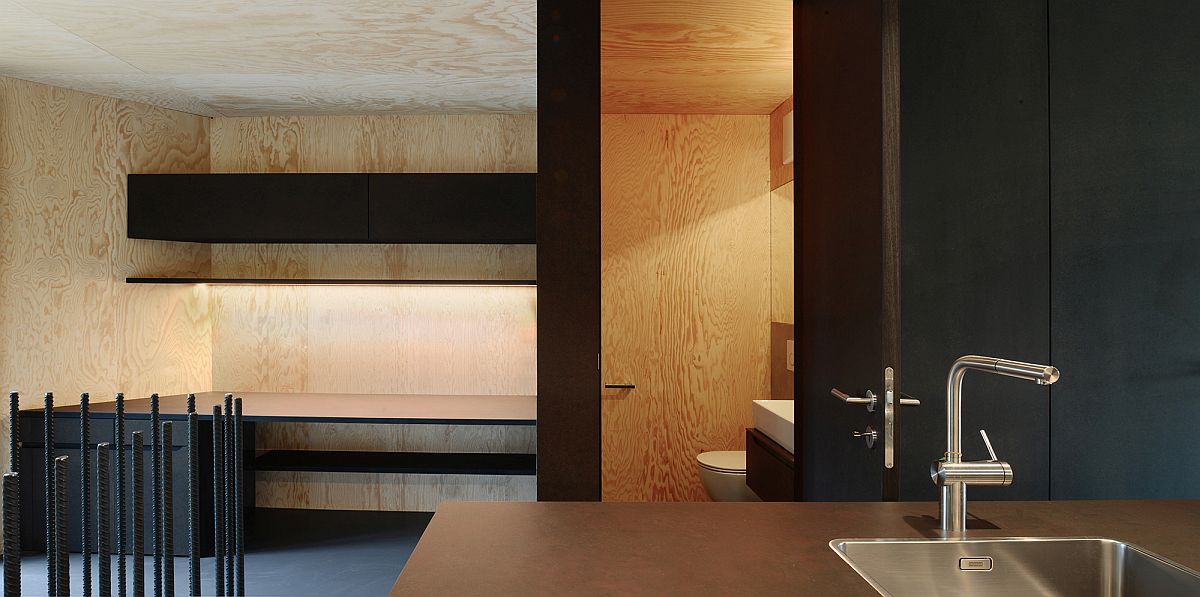 Phòng tắm nhỏ được bố trí phía sau đảo bếp, “trung thành” với vật liệu gỗ ốp tường với đường vân tự nhiên đẹp mắt, kết hợp cùng hệ thống đèn tạo cảm giác ấm áp cho không gian thư giãn.