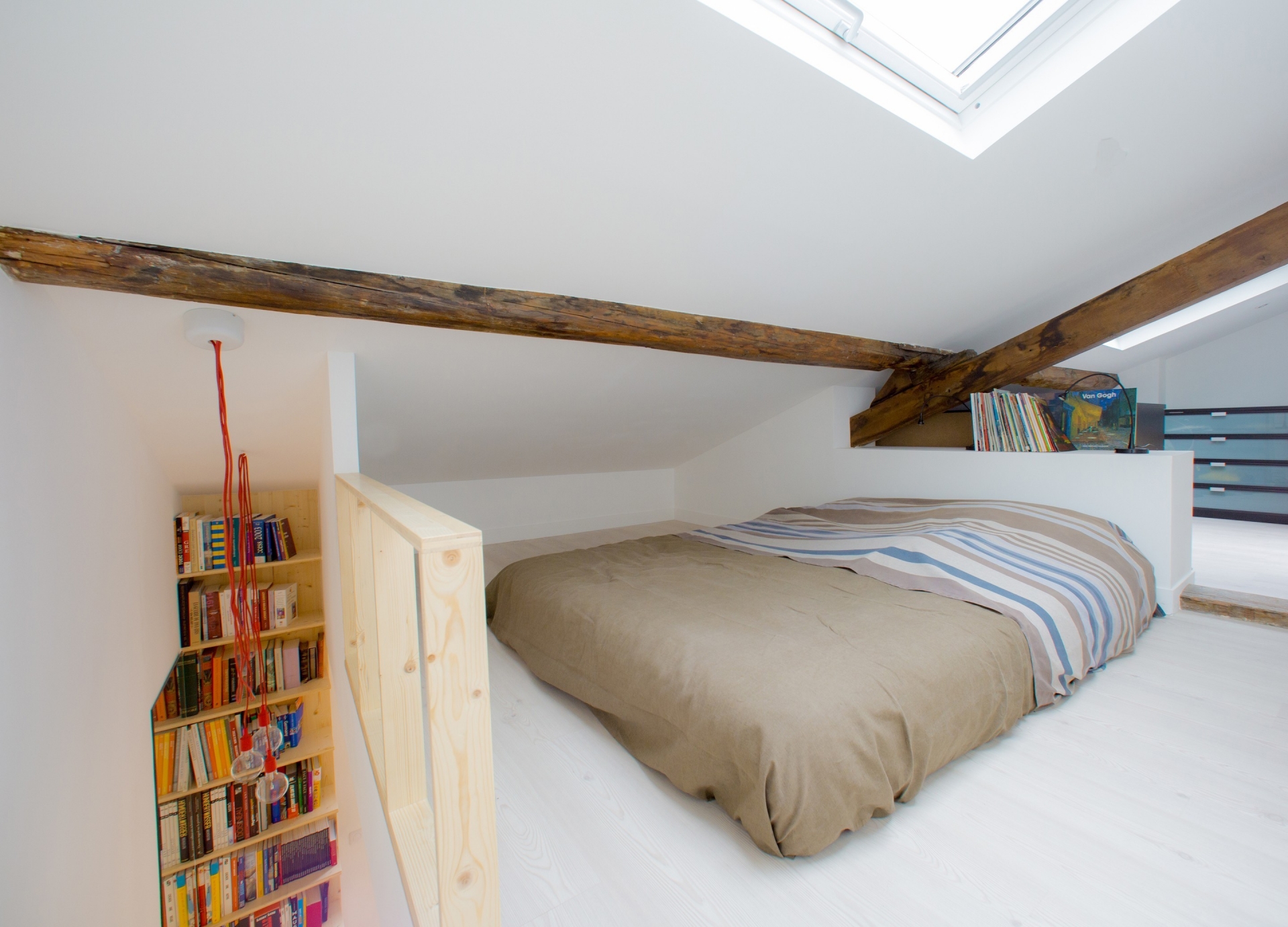 Phòng ngủ trên gác thiết kế tối giản với tấm đệm dày thay thế cho chiếc giường, dầm gỗ lộ ra ngoài cho cái nhìn mộc mạc. 