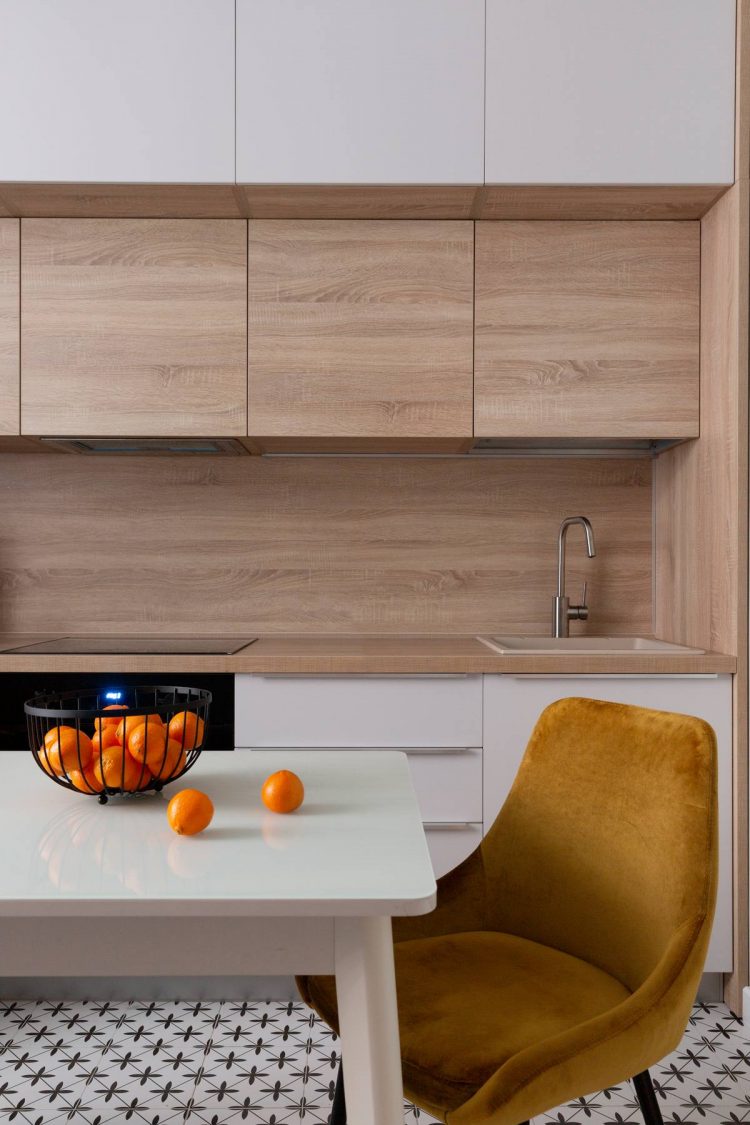 Phòng bếp thiết kế kiểu chữ I phù hợp với cấu trúc căn hộ nhỏ, vừa không chiếm nhiều diện tích nhưng vẫn đảm bảo tiện nghi đầy đủ cho khu vực nấu nướng. Hệ tủ bếp sử dụng 2 gam màu trắng và gỗ tự nhiên cho cảm giác tươi sáng và thoáng đãng.