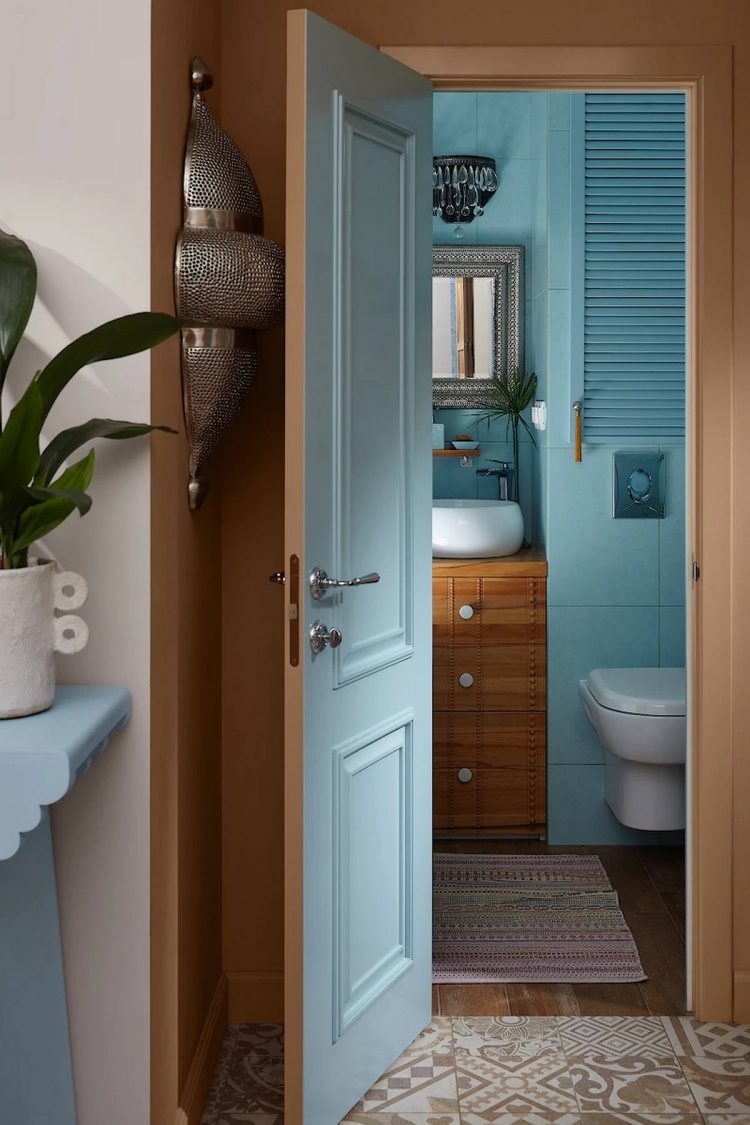 Khu vực phòng tắm nằm gần lối ra vào của căn hộ, với cánh cửa mặt ngoài sơn màu đất nung, mặt trong sơn màu xanh ngọc tạo nên sự chuyển đổi bất ngờ cho thị giác người nhìn.