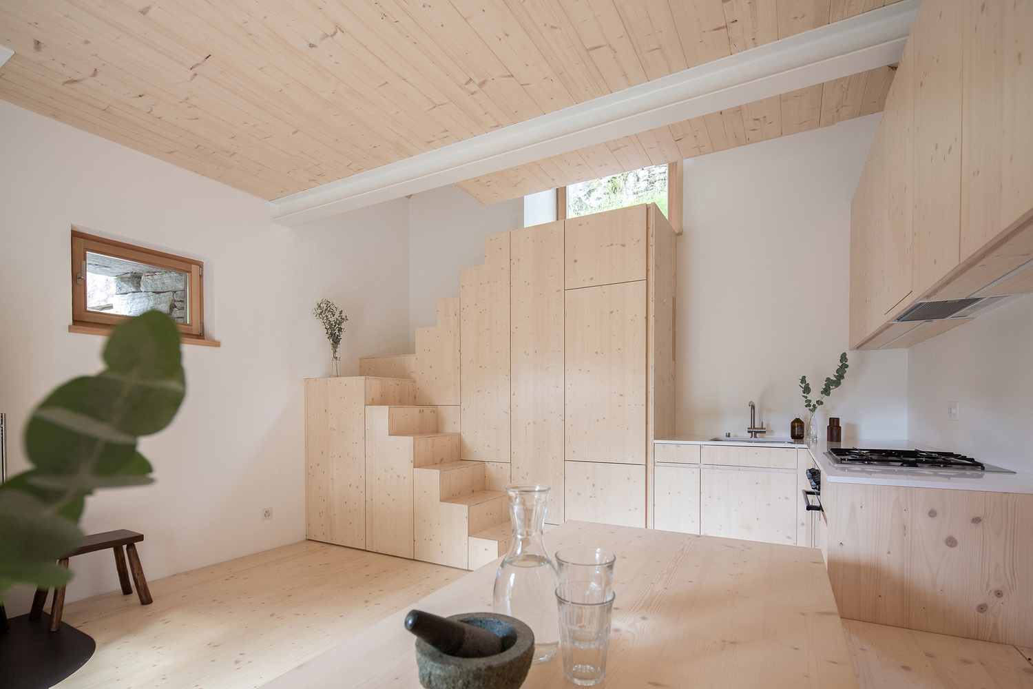 Cầu thang do Rafael Schmid Architekten thiết kế đóng vai trò như bộ tủ khép kín với bề mặt gỗ tươi sáng tương tự nội thất phòng bếp, tạo ra khu vực tích hợp độc đáo.