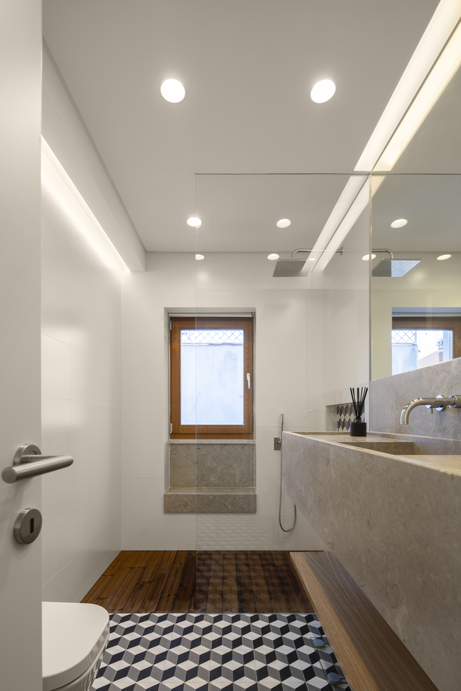 Khung cửa gỗ, sàn phòng tắm gỗ kết hợp với sàn lát gạch bông cổ điển ở nhà vệ sinh và bồn rửa tay bằng đá với vòi rửa kim loại,... tất cả tạo nên sự phân vùng bằng vật liệu xây dựng đẹp mắt.