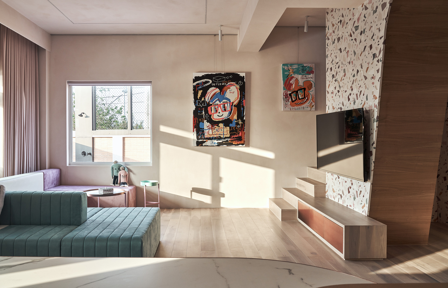 Phòng khách với sofa thiết kế kiểu module nhiều màu sắc tím, trắng, hồng, xanh nổi bật. Đối diện là tivi treo trên bức tường ốp gạch terrazzo cho cái nhìn tươi tắn.