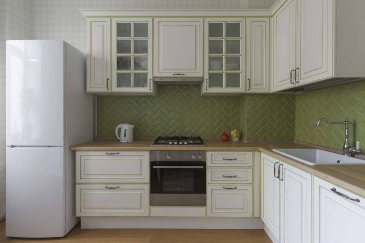 Phòng bếp thiết kế chữ L, phù hợp cấu trúc căn hộ, với gam màu trắng chủ đạo cùng mặt bàn gỗ. Hệ tủ rộng rãi cả phần trên và dưới tạo không gian lưu trữ thoải mái cho người nội trợ.