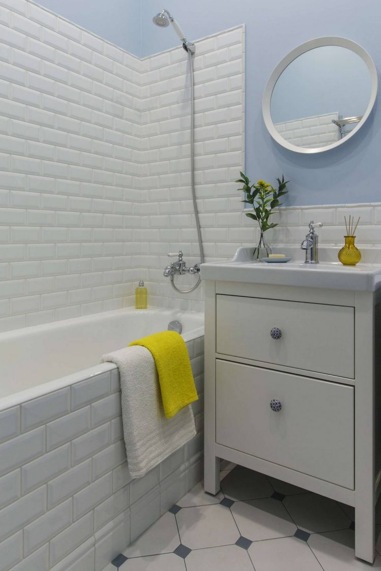 Tủ lưu trữ kết hợp bồn rửa tay tiện ích, bên trên là tấm gương tròn treo tường đẹp mắt. Những món phụ kiện nho nhỏ màu vàng sắp xếp trên bồn rửa hoặc chiếc khăn tắm khiến không gian trẻ trung, bắt mắt hơn.