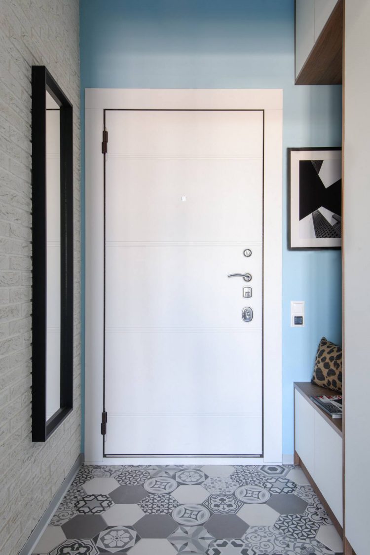 Nền tường xanh dịu mắt bao quanh cánh cửa ra vào màu trắng, tấm gương lớn đối diện góc nghỉ chân cùng những viên gạch lát sàn sắp xếp ngẫu hứng tạo nên sự bắt mắt cho lối vào căn hộ.