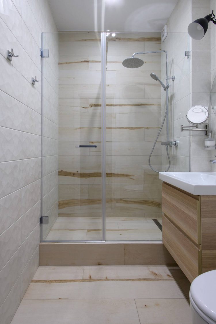 Từ sàn nhà cho đến bức tường bên trong buồng tắm được ốp gạch hoa văn giả gỗ tạo sự liên kết với tủ lưu trữ bên dưới bồn rửa cho cái nhìn ấm áp, mộc mạc.