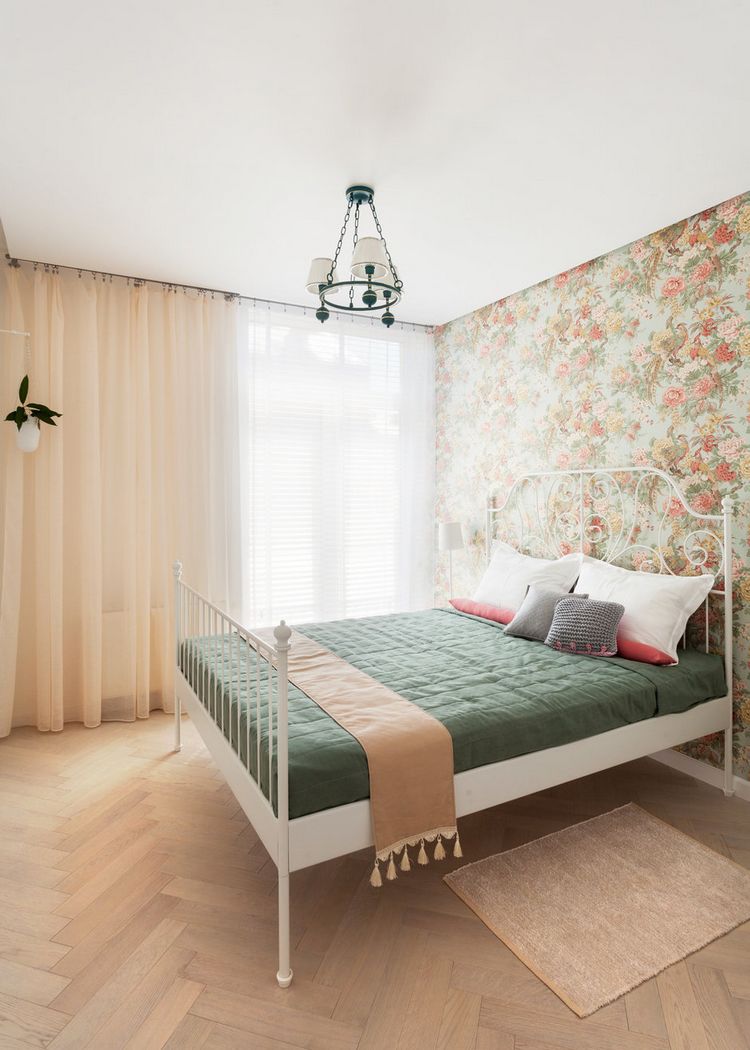 Phòng ngủ được thiết kế khác biệt so với khu vực sinh hoạt chung. Sàn gỗ họa tiết hình xương cá, rèm cửa màu trắng và cam nhạt kết hợp ga trải giường màu xanh rêu thời trang và nổi bật.