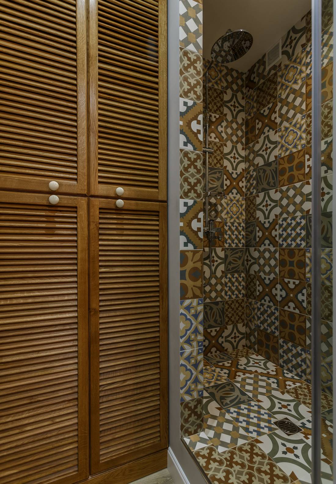 Tủ lưu trữ gỗ kiểu dáng cổ điển có kích thước từ trần đến sàn nhà để tối ưu hóa không gian. Đặc biệt nhất là buồng tắm vòi hoa sen với cửa kính trong suốt và toàn bộ bức tường bên trong được láy gạch bông như một bức tranh nghệ thuật đầy ngẫu hứng.