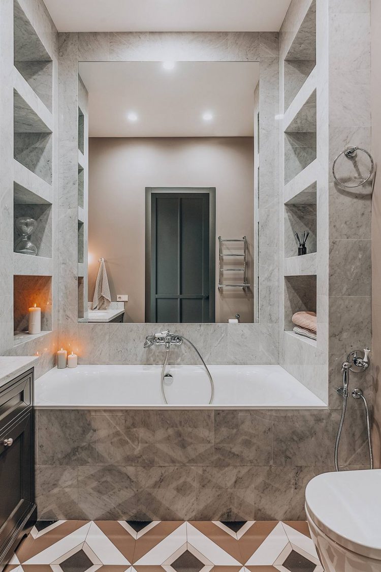 Sàn phòng tắm có sự tương đồng với lối ra vào căn hộ để tạo sự liên kết. Bồn tắm được xây cao để tạo thành một khối riêng tư phân vùng với khu vực toilet. Hốc tường xây bằng đá để tăng không gian lưu trữ cùng những ánh nến lãng mạn, ấm áp.