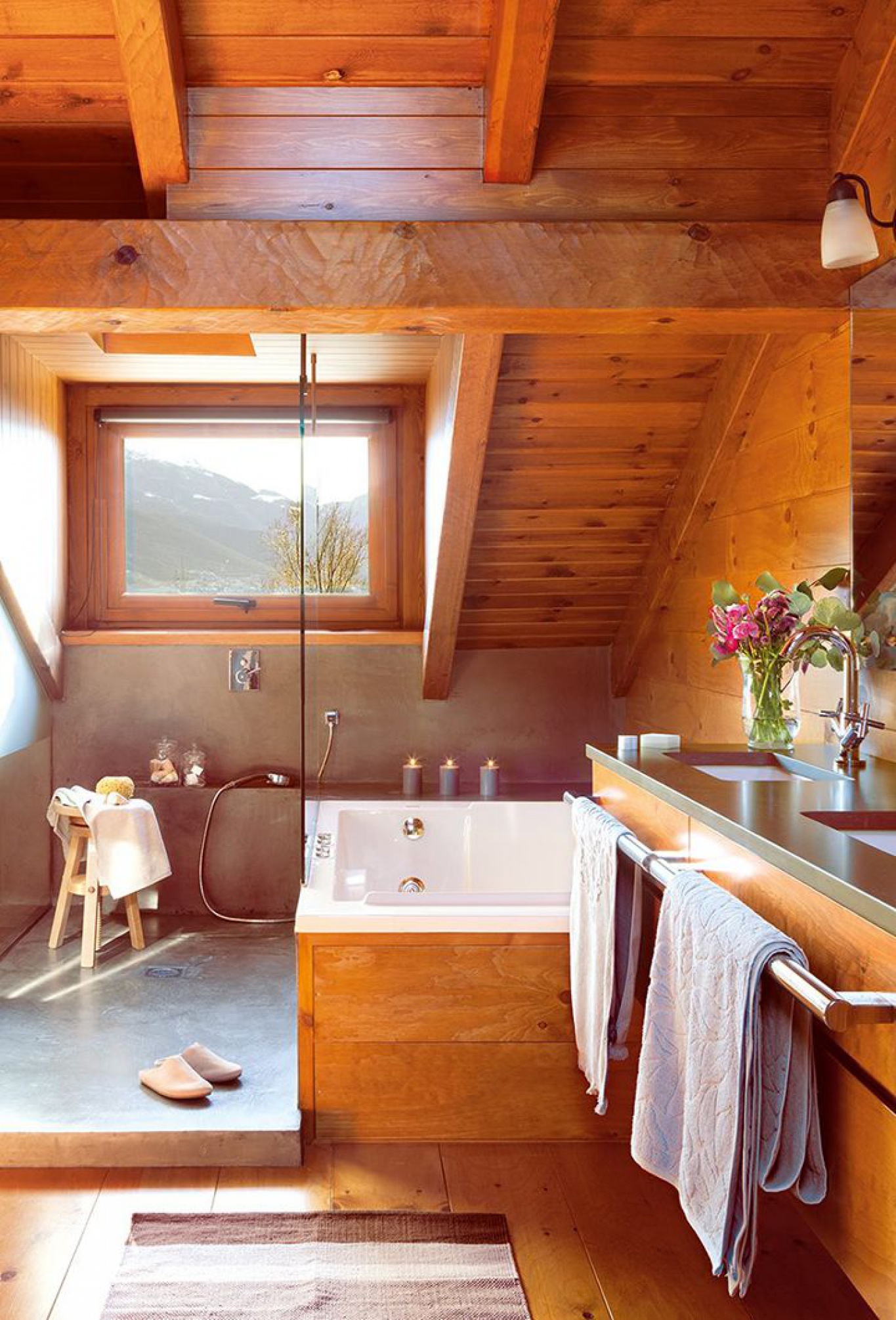 Một phòng tắm trên tầng áp mái với phong cách mộc mạc, ấm áp vô cùng. Nội thất được ốp bằng gỗ màu hổ phách, khung cửa hình chữ nhật nhỏ xinh nhìn ra khung cảnh núi non thơ mộng bên ngoài.