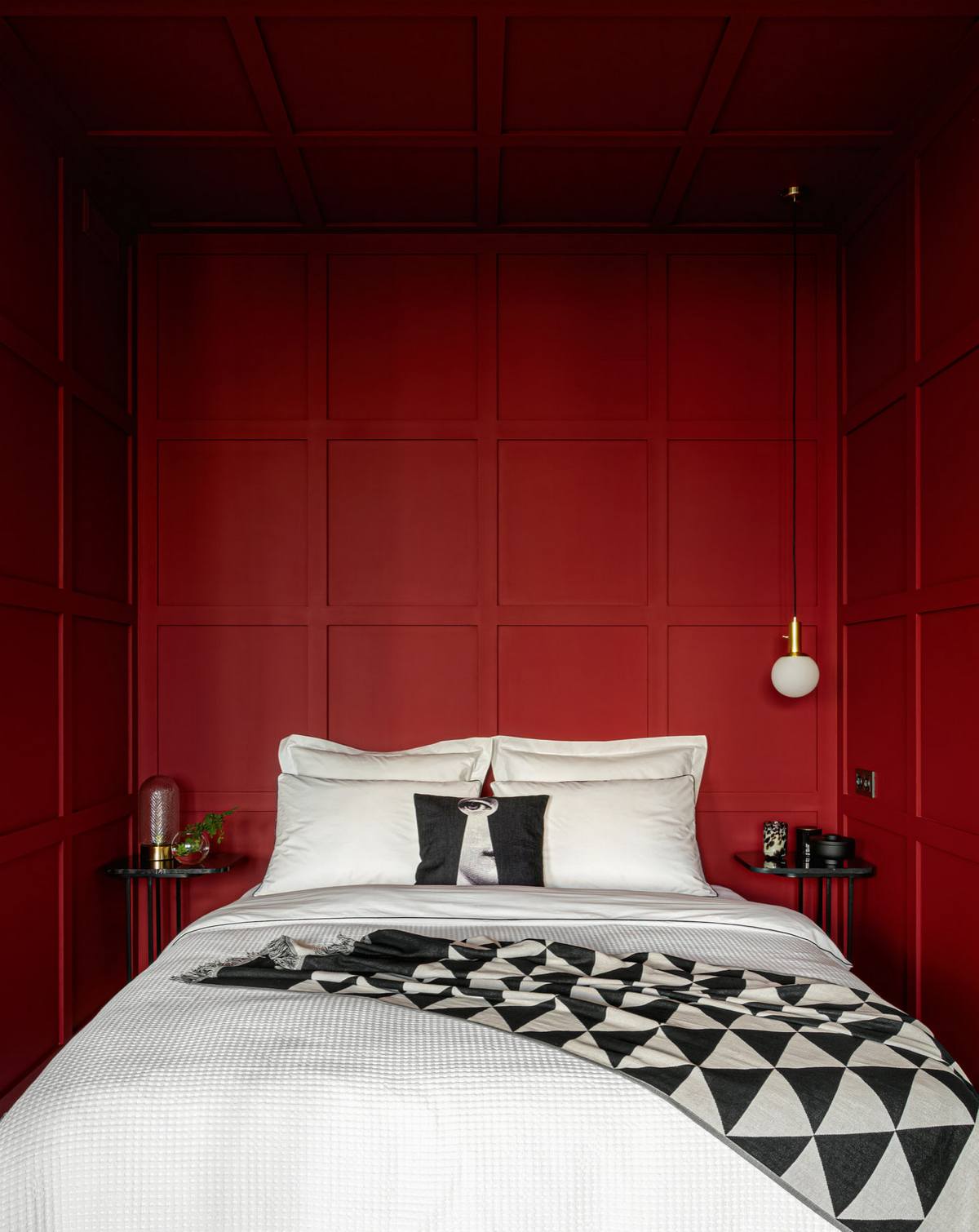 Nếu xuyên suốt căn hộ là 2 gam màu trắng đen cổ điển thì tại phòng khách, 'cặp đôi' này được sử dụng cho giường ngủ với chăn ga gối và mềm mỏng. Nổi bật hơn cả là sắc màu đỏ tía của 3 mặt bức tường bao quanh phòng ngủ.