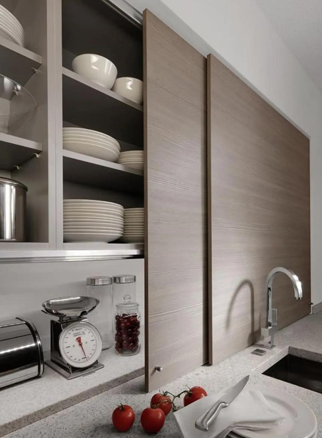 Cửa trượt bằng gỗ giúp 'che giấu' hệ thống tủ lưu trữ mở trên bức tường phòng bếp, sau khi sử dụng chỉ cần một thao tác đẩy nhẹ là bạn chỉ thấy một bức tường gỗ mộc mạc mà thôi.